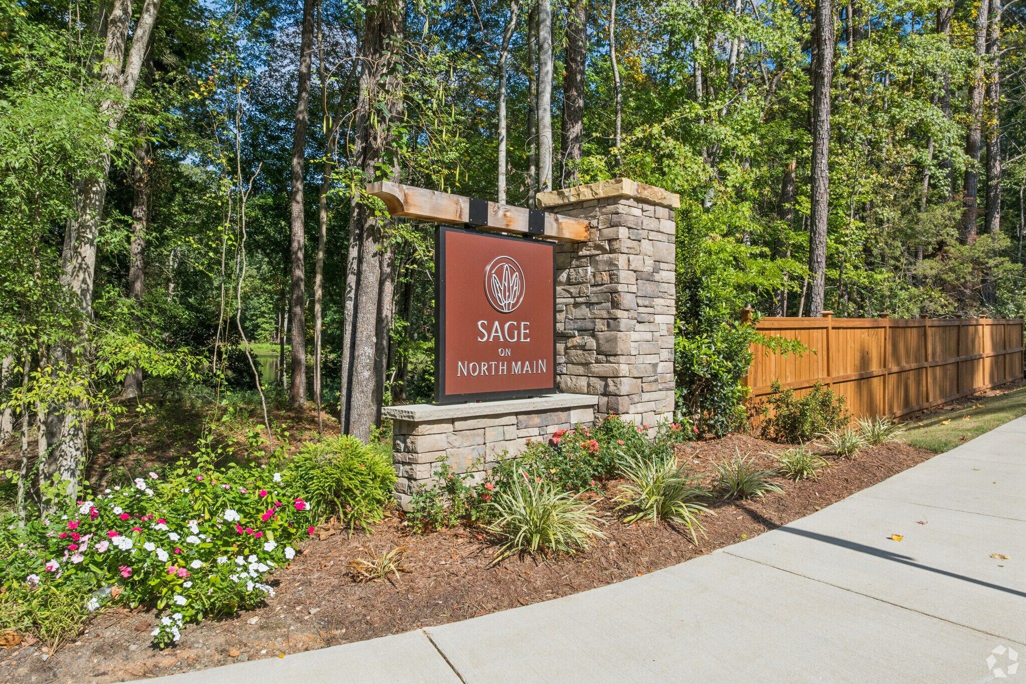 Stone community entrance monument with Sage on North Main sign surrounded by landscaped flowers at Davidson Homes neighborhood in Wake Forest, NC