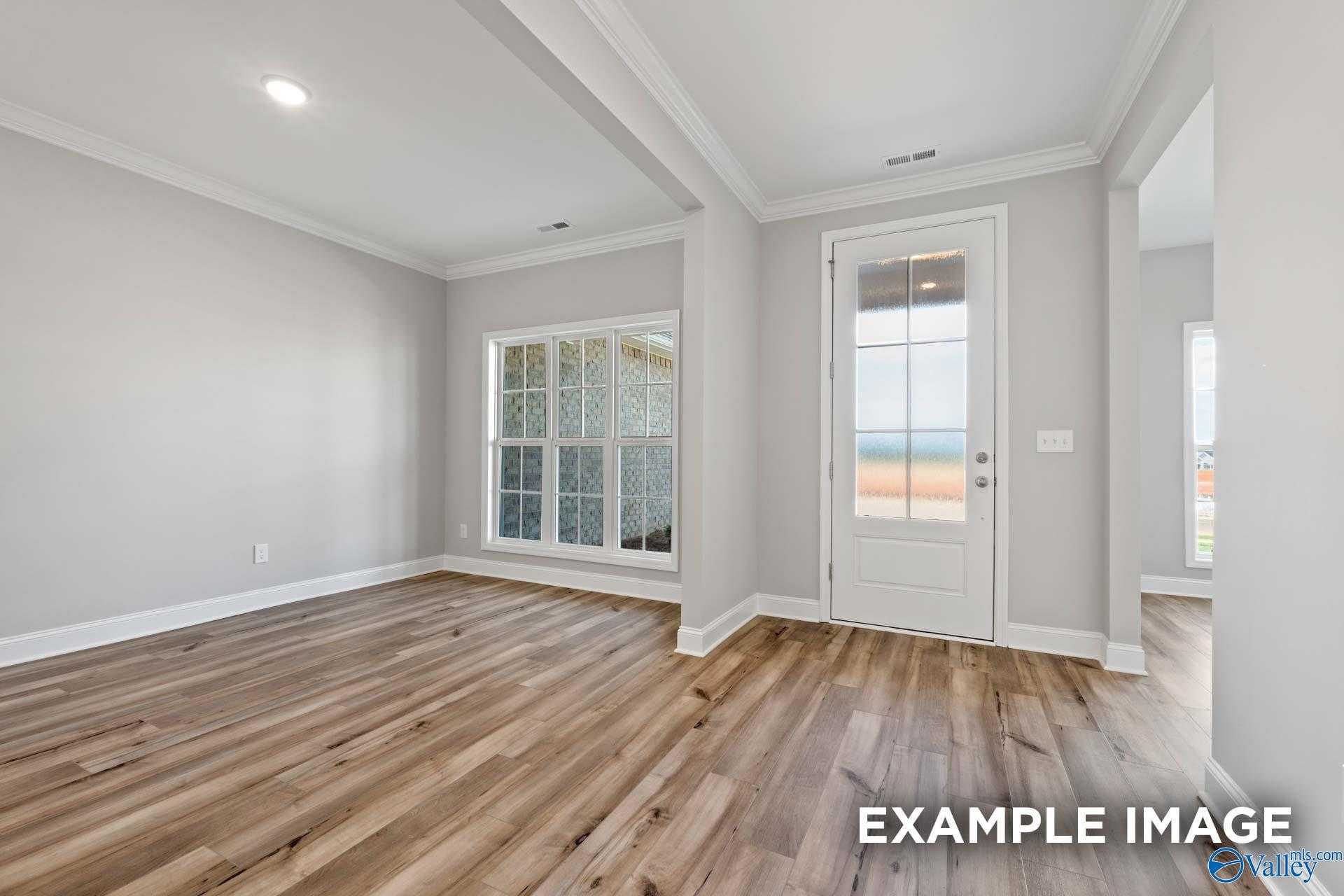 Bright living room with light gray walls, hardwood floors, and large bay window in Davidson Homes The Richmond D, Huntsville AL