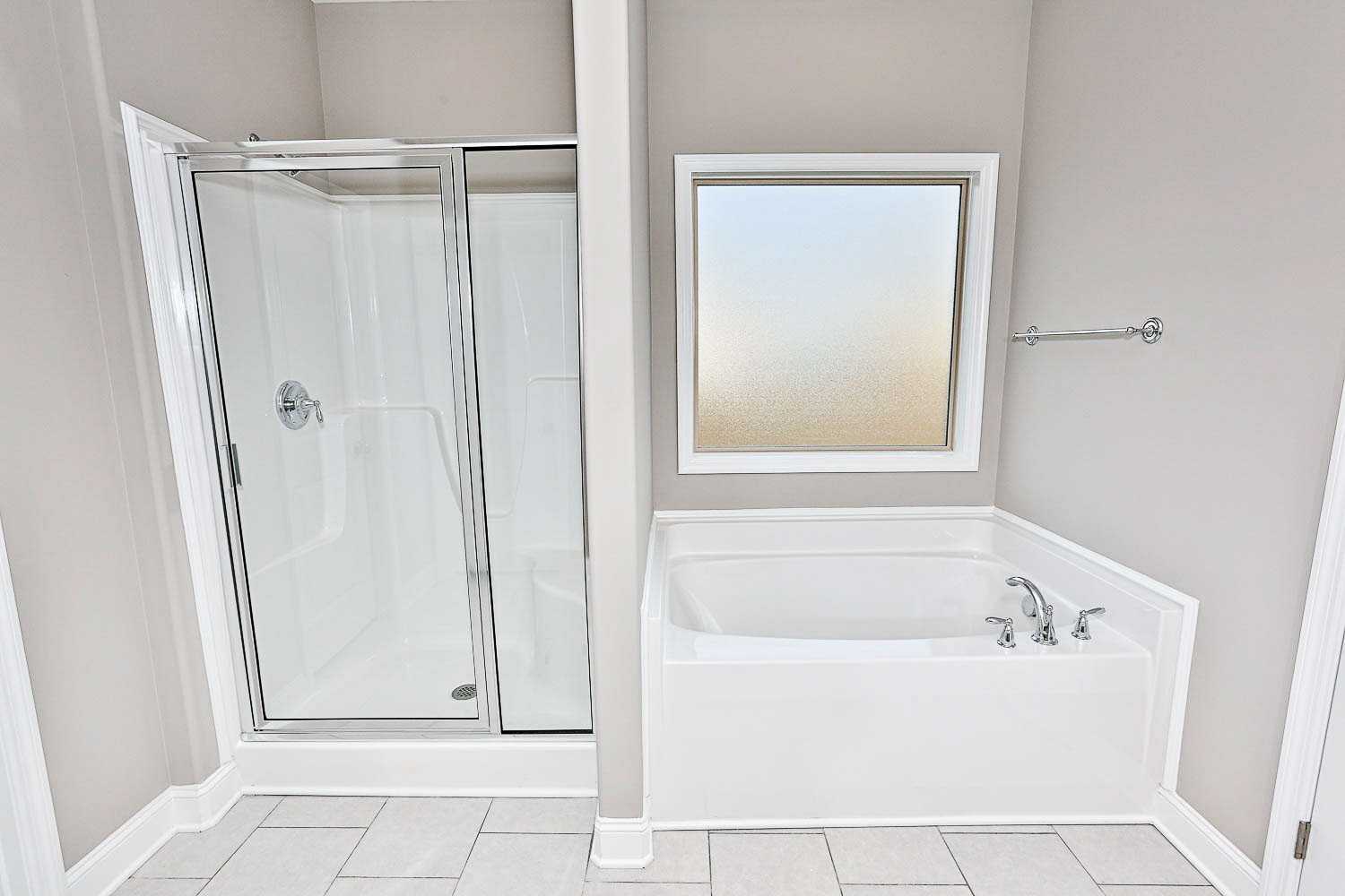 Master bathroom in The Montgomery featuring glass walk-in shower, corner soaking tub, frosted window