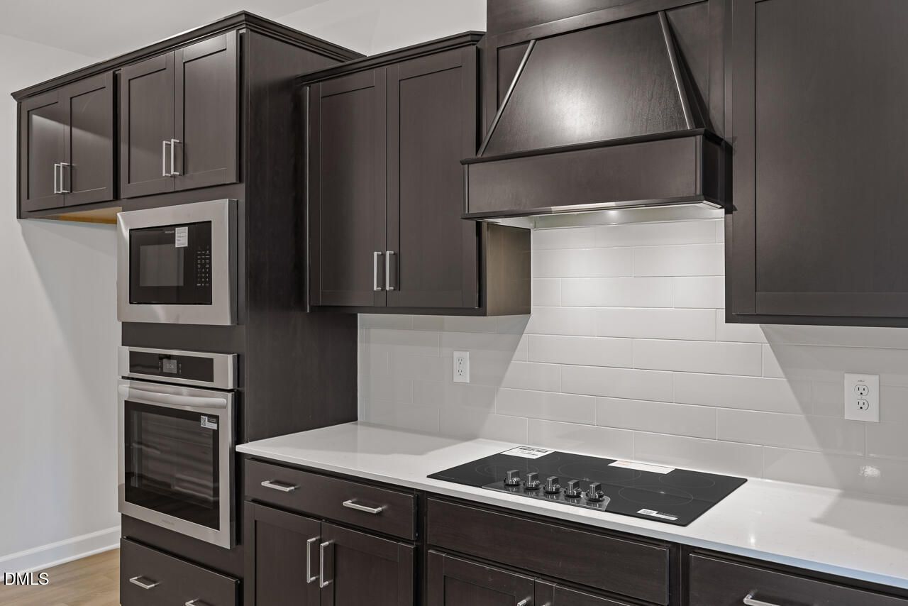 Modern kitchen with dark espresso cabinets, white countertops, and stainless appliances in Hickory II B, Wellers Knoll home.