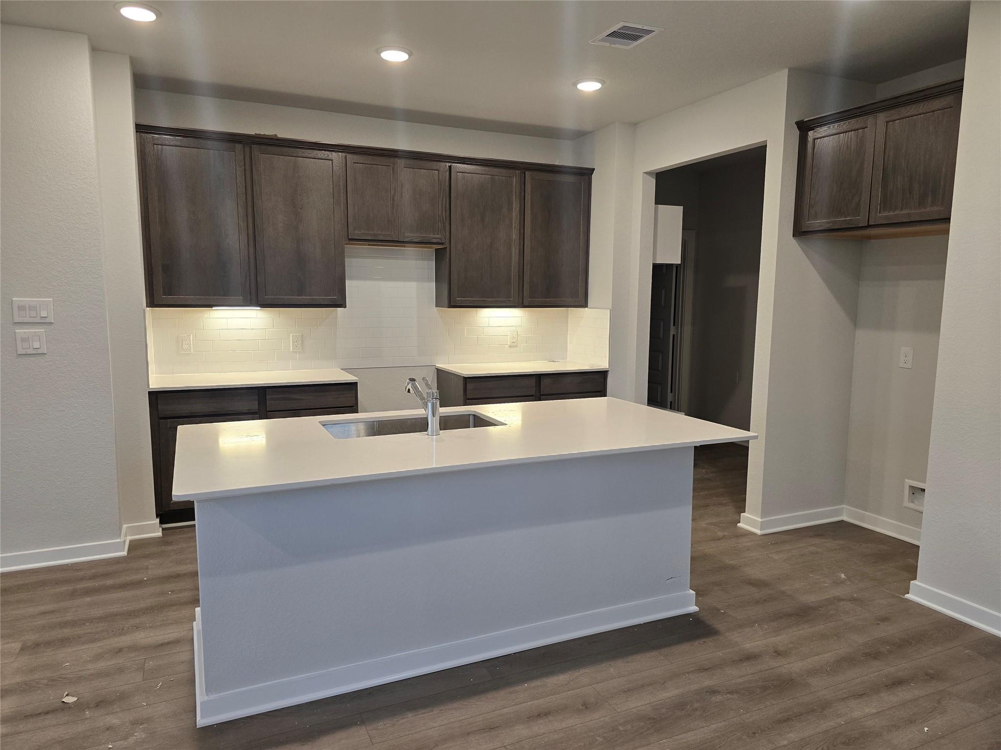 Modern kitchen with white quartz island, dark wood cabinets, stainless fridge in The Brazos E 5-bedroom home, Cleveland TX