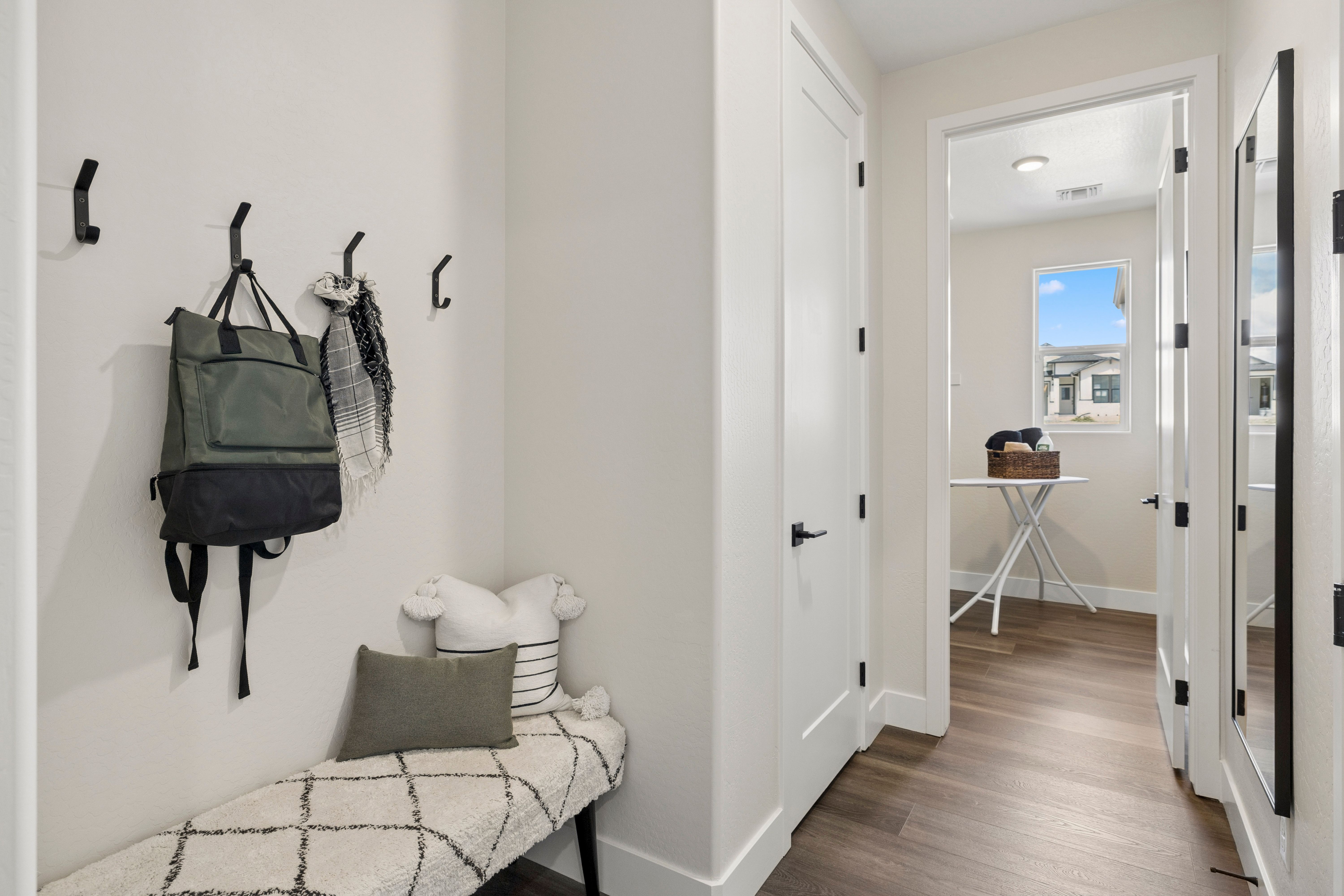 Cozy mudroom entry with wall hooks, green backpack, scarf, cushioned bench and wood floors at South Ranch Western Collection in Prescott AZ