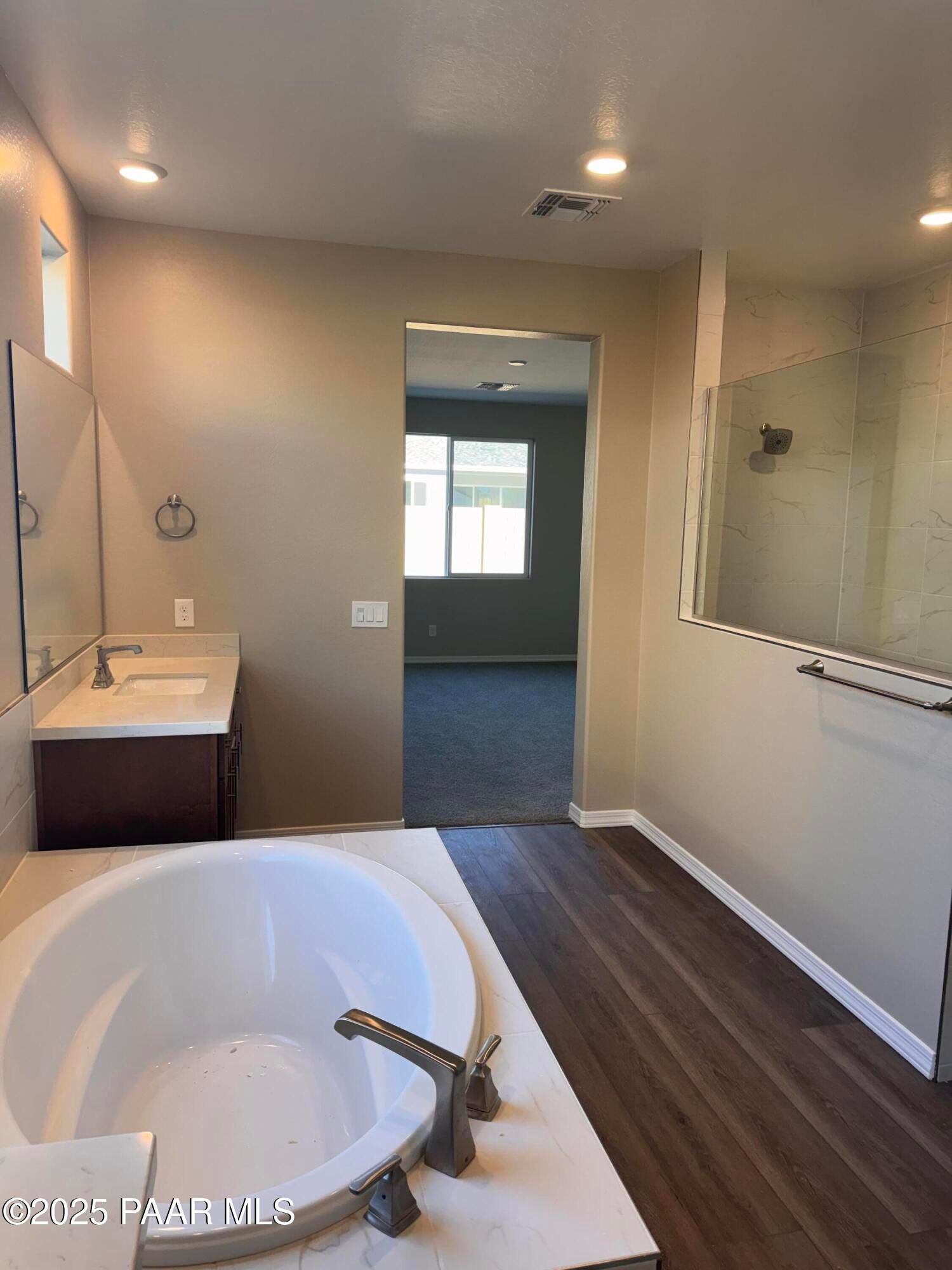 Elegant master bathroom with freestanding oval tub, glass shower, and wood floors in Davidson Homes Sunrise II A, Prescott, AZ