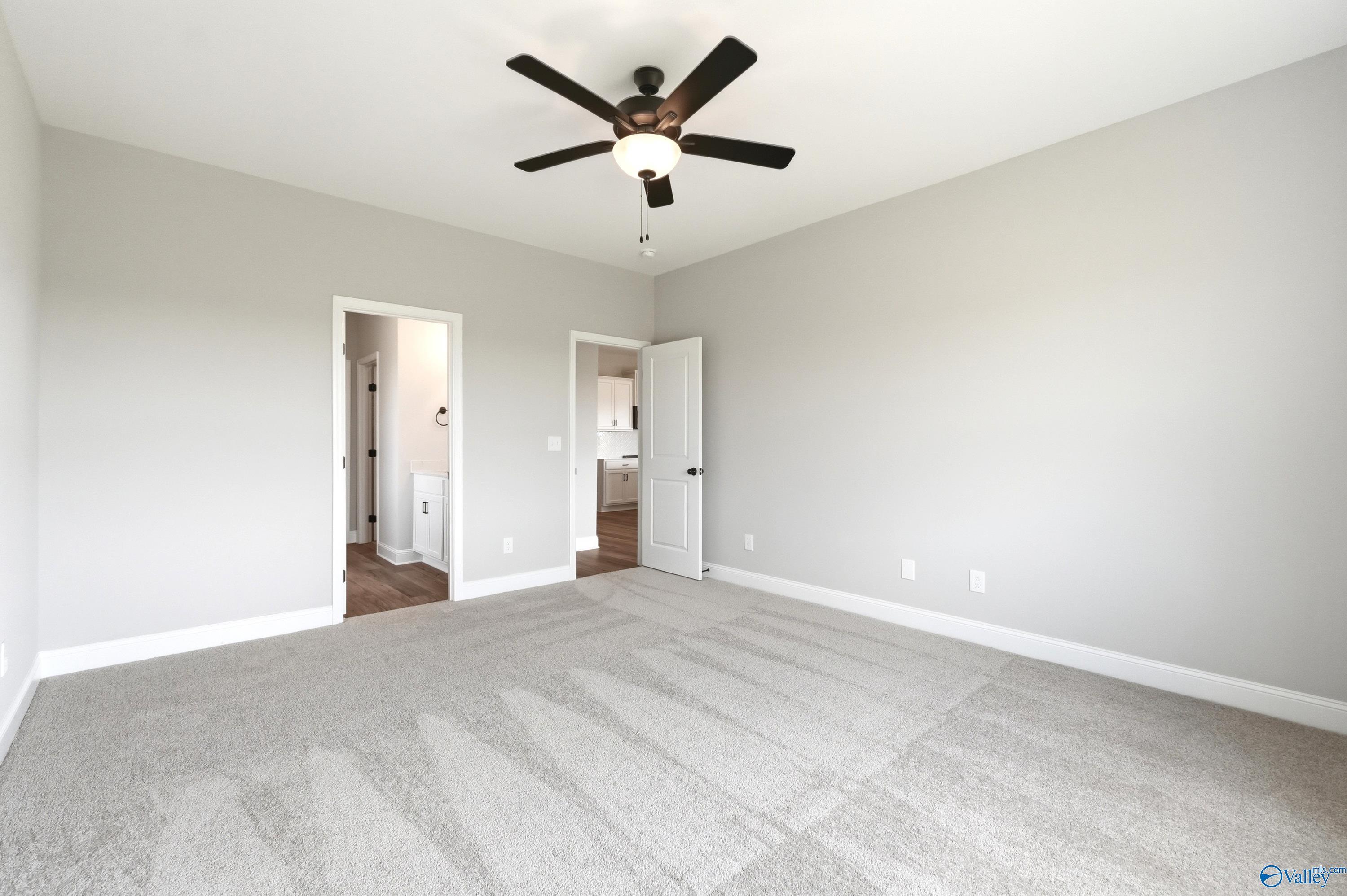 Spacious bedroom with grey carpet and ceiling fan in The Daphne D floor plan by Davidson Homes in Creekside, Harvest, AL