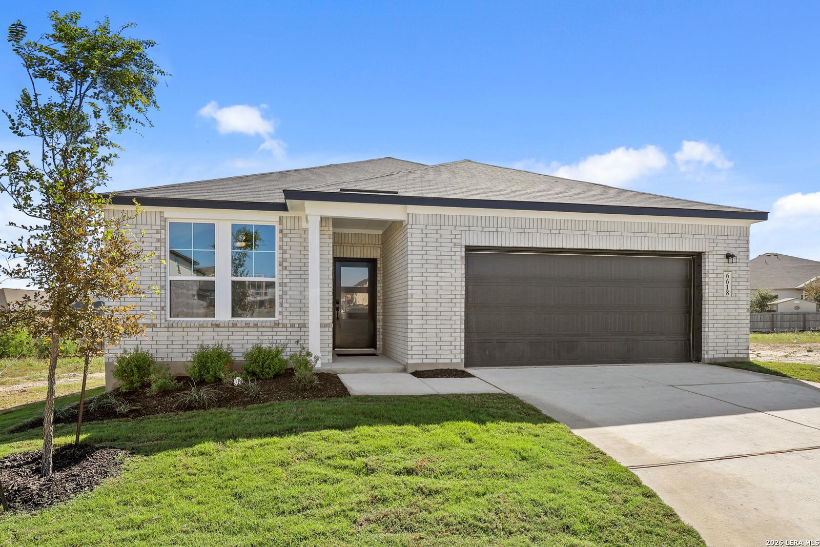 White brick exterior of Davidson Homes The Glenwood E, 3-bed 2-car garage home with landscaped yard in Comanche Ridge, San Antonio