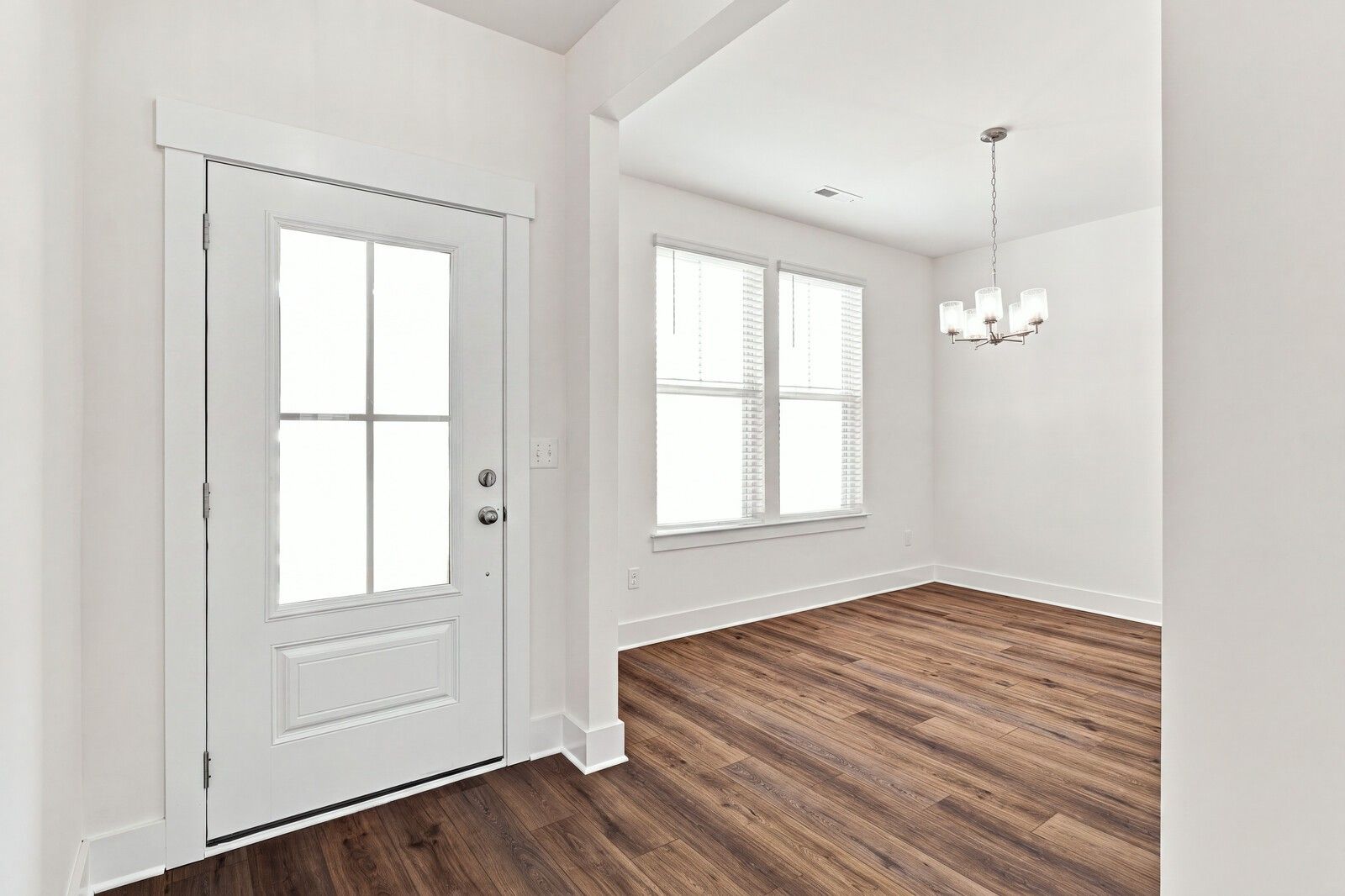 Bright foyer with glass-panel front door, luxury vinyl plank flooring, and chandelier in Davidson Homes Willow C, Gallatin TN