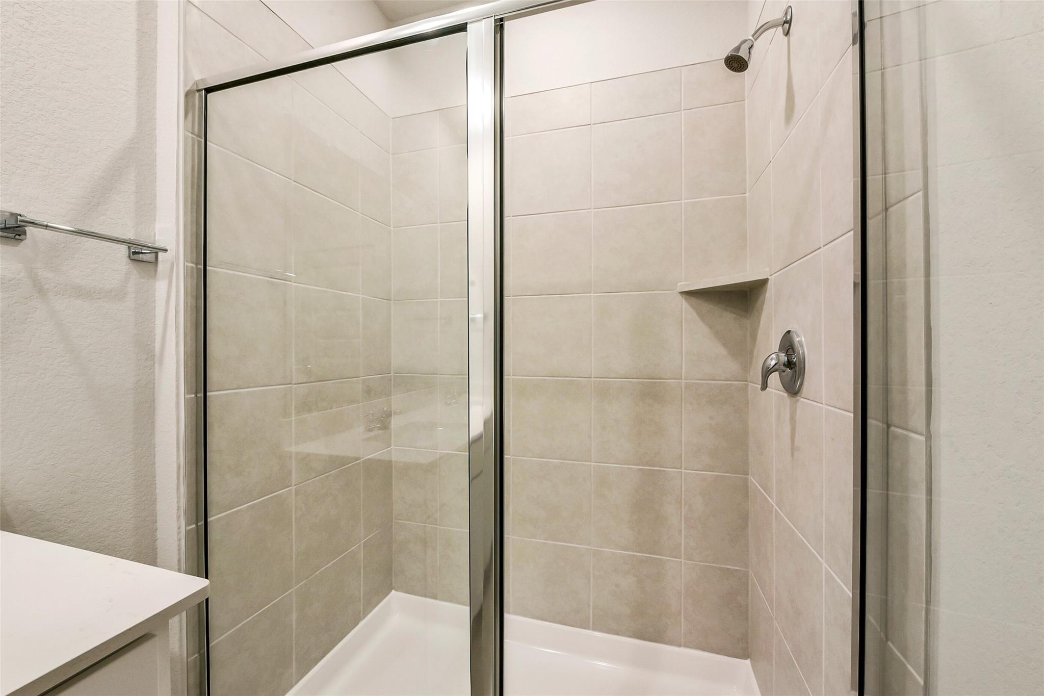 Modern frameless glass walk-in shower with white subway tiles in master bathroom, Davidson Homes The Comal G, Dayton Texas