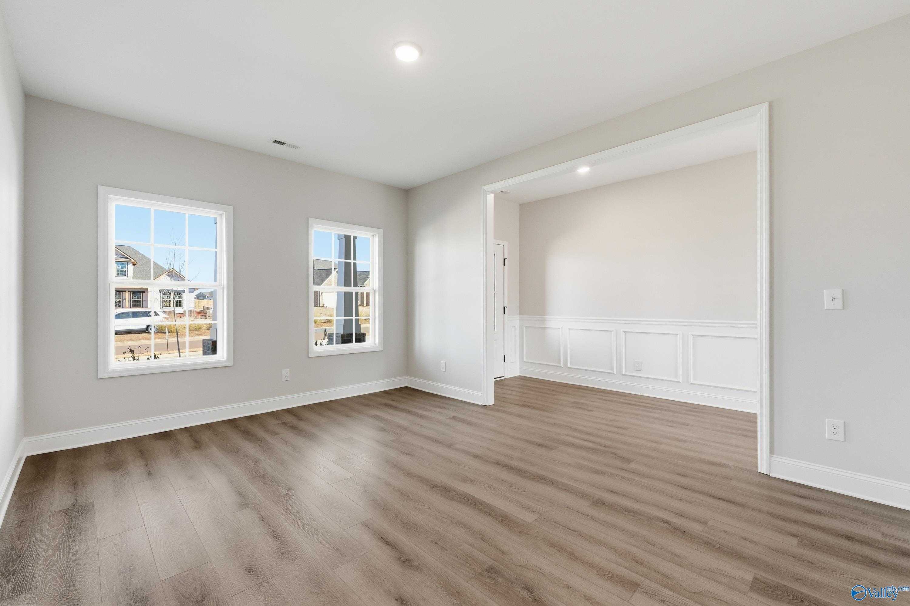 Bright secondary bedroom with wainscoting, large windows, and luxury vinyl plank flooring in Davidson Homes Chelsea C, Harvest AL