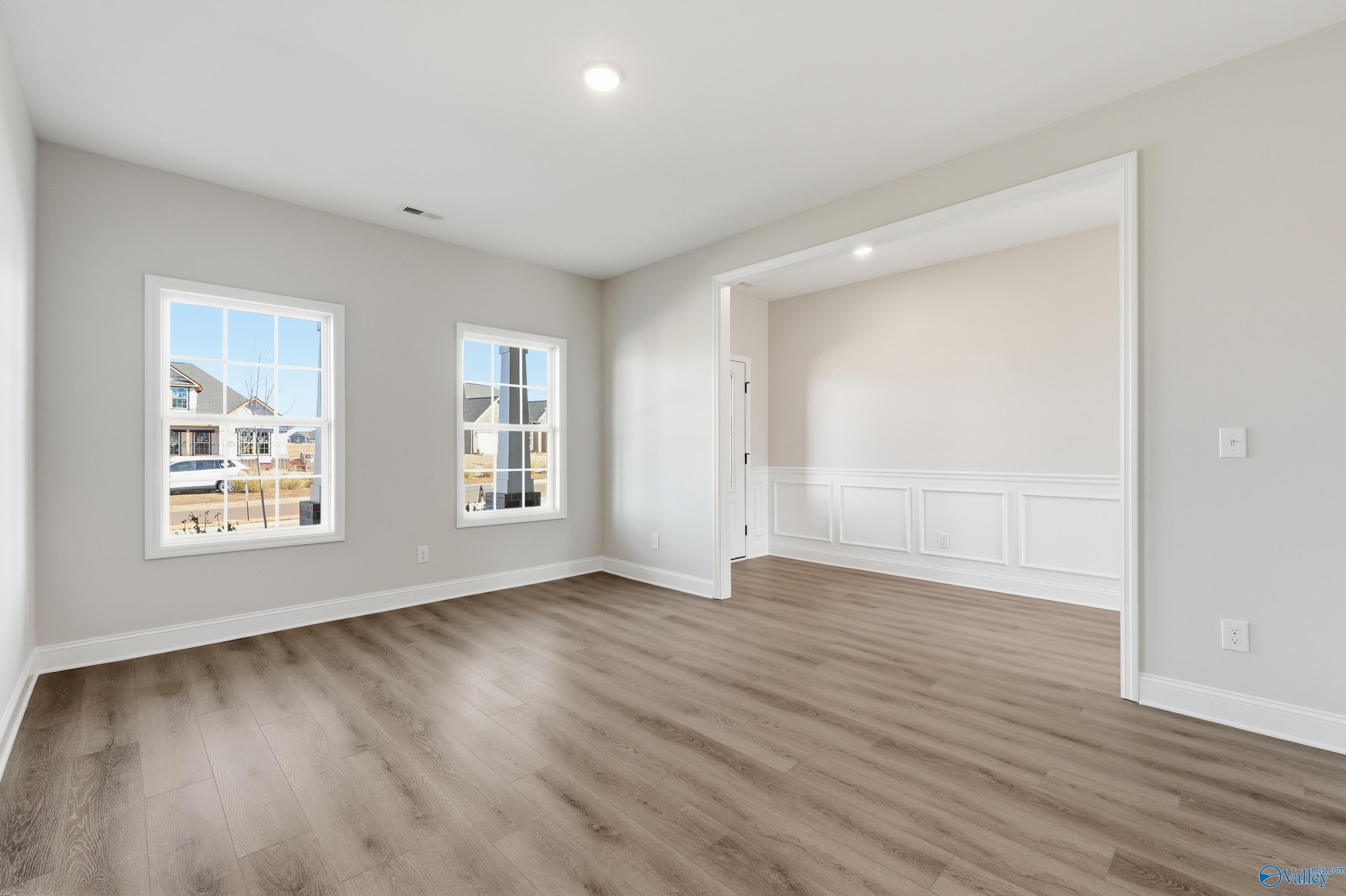 Bright secondary bedroom with wainscoting, large windows, and luxury vinyl plank flooring in Davidson Homes Chelsea C, Harvest AL