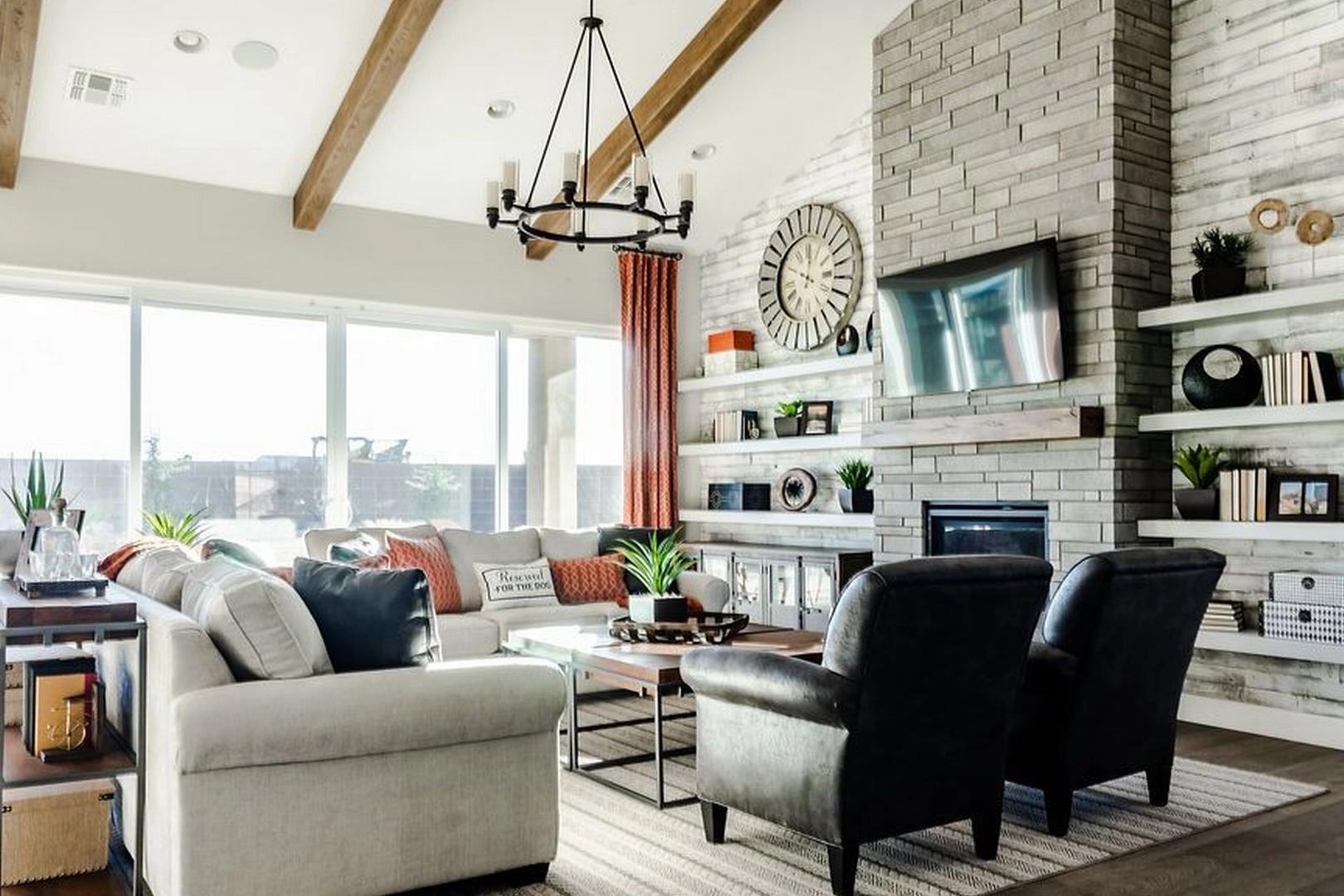Spacious living room in Westwood Prescott AZ by Davidson Homes featuring exposed wood beams, stone gas fireplace, and large sunny windows