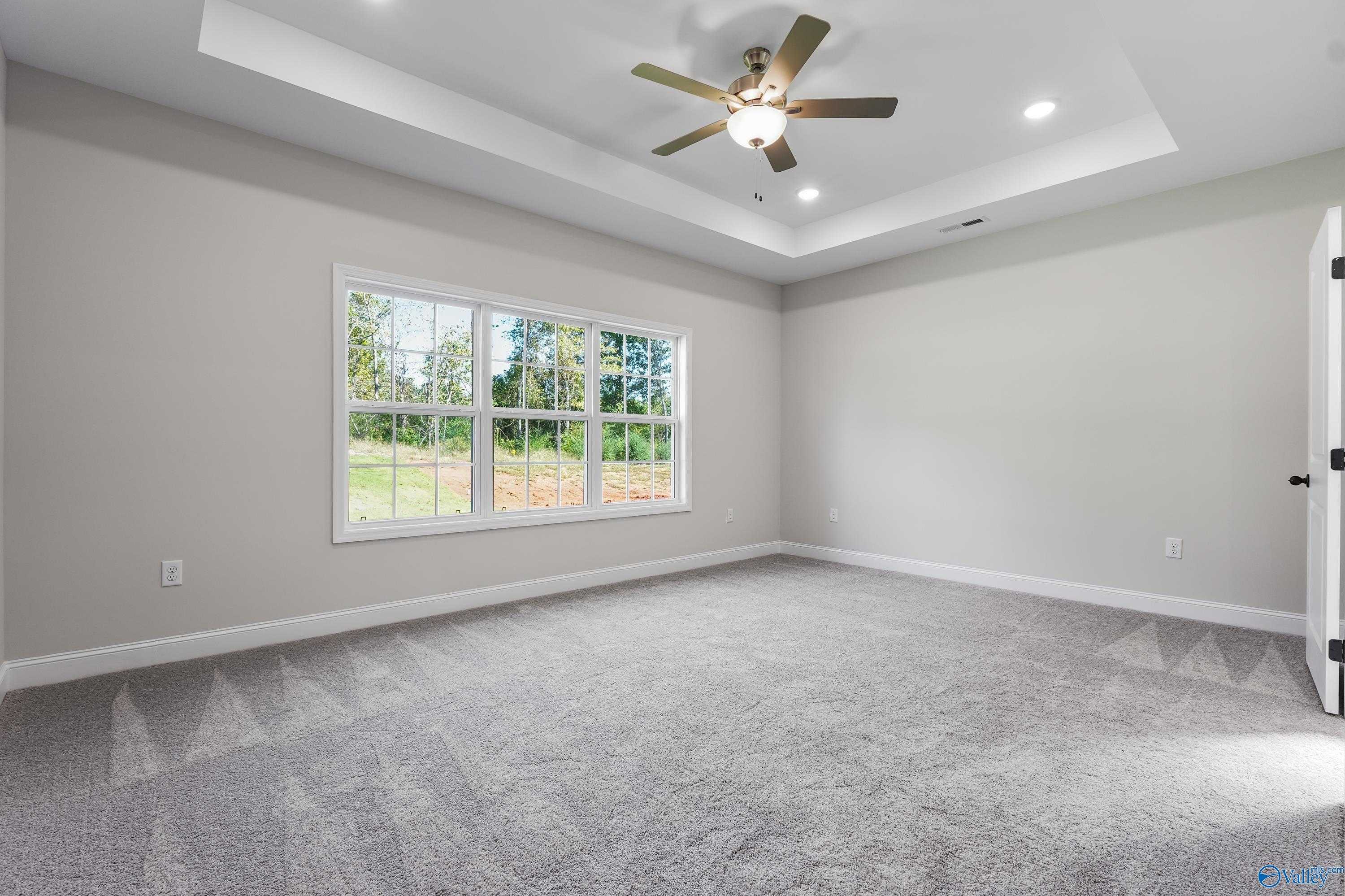 Bright bedroom with large windows, gray carpet, ceiling fan in Davidson Homes Montgomery C, Decatur Alabama