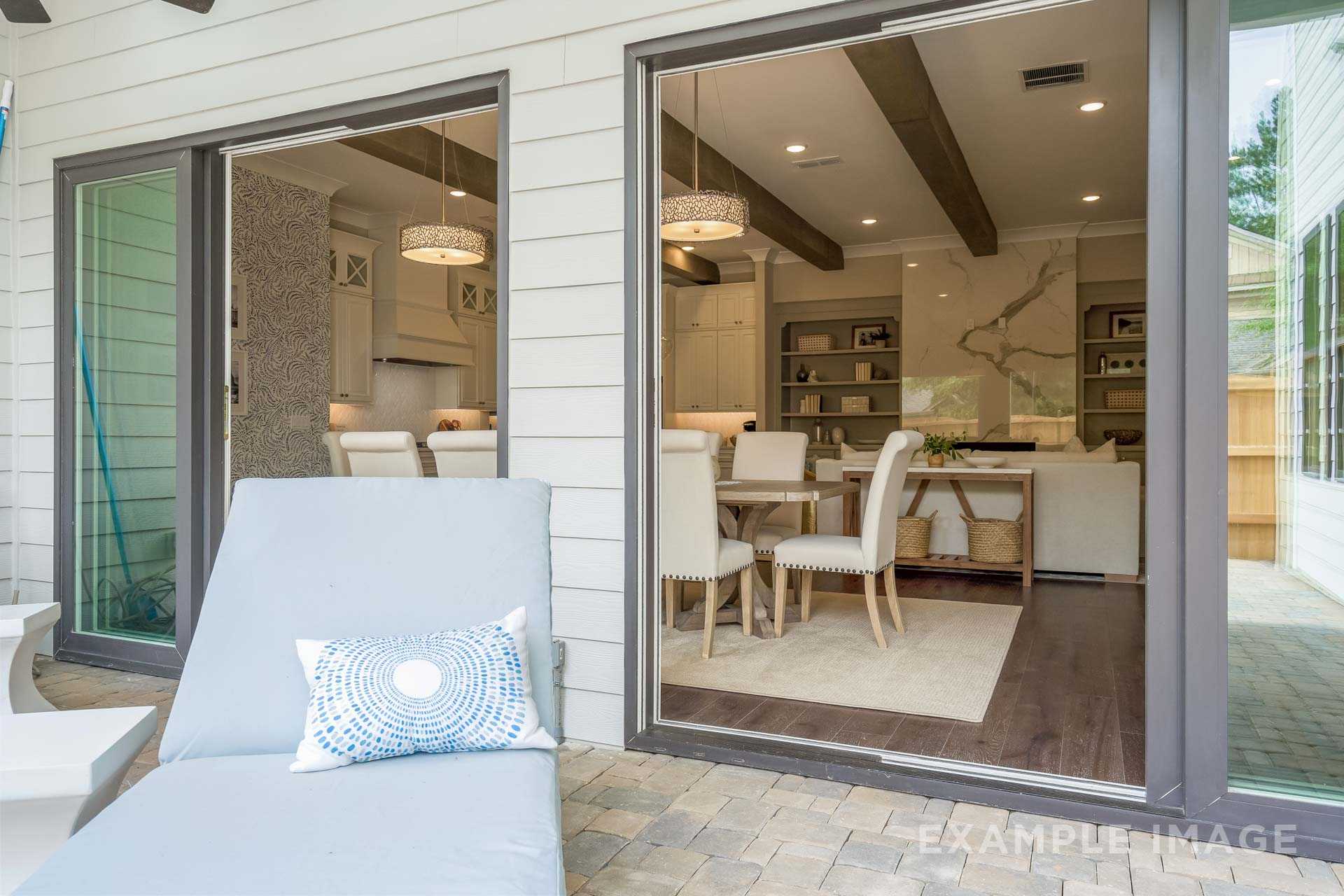 Spacious patio with blue chaise lounge through glass doors to dining area and open kitchen in The Seaside by Davidson Homes