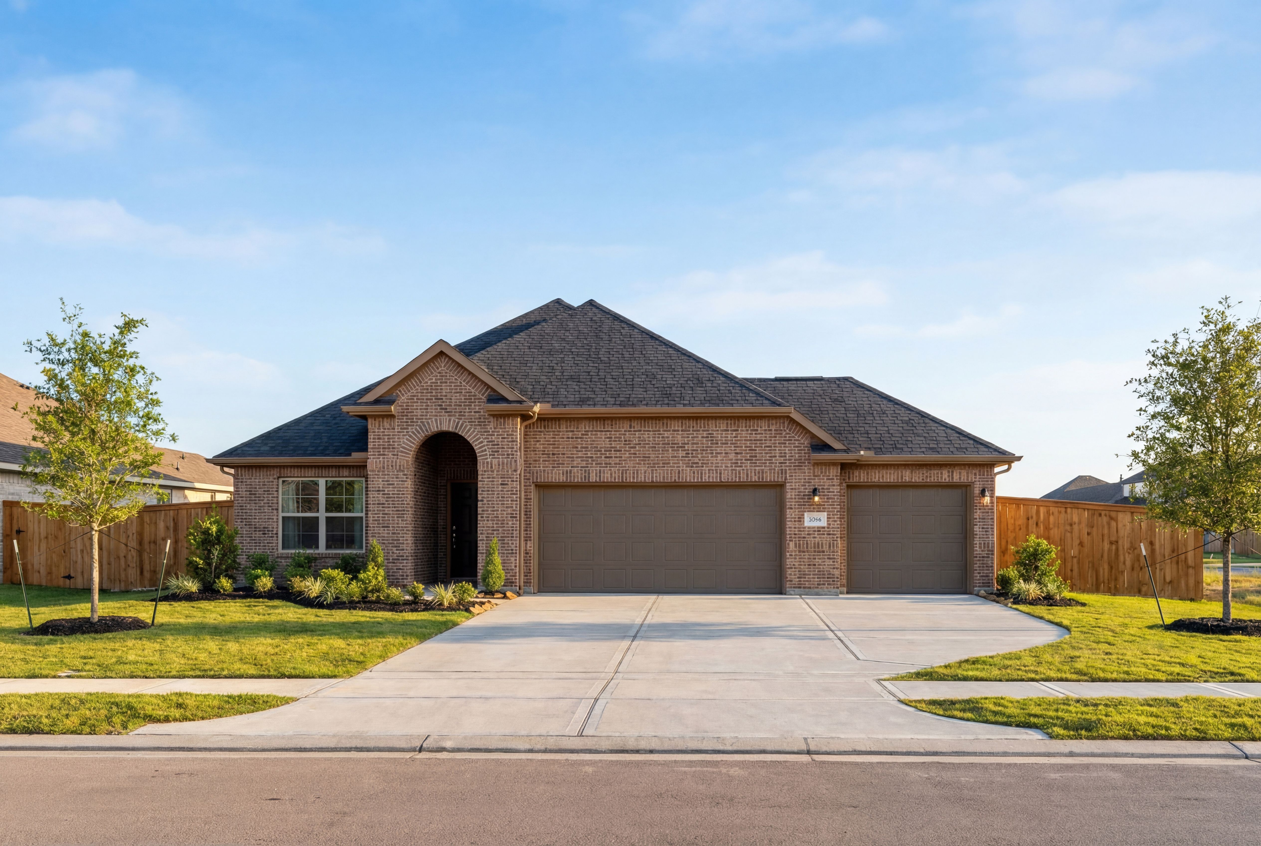 Brick elevation of The Acadia A 1-story home with 3-car garage, arched entry, and landscaped yard in Rosharon, Texas