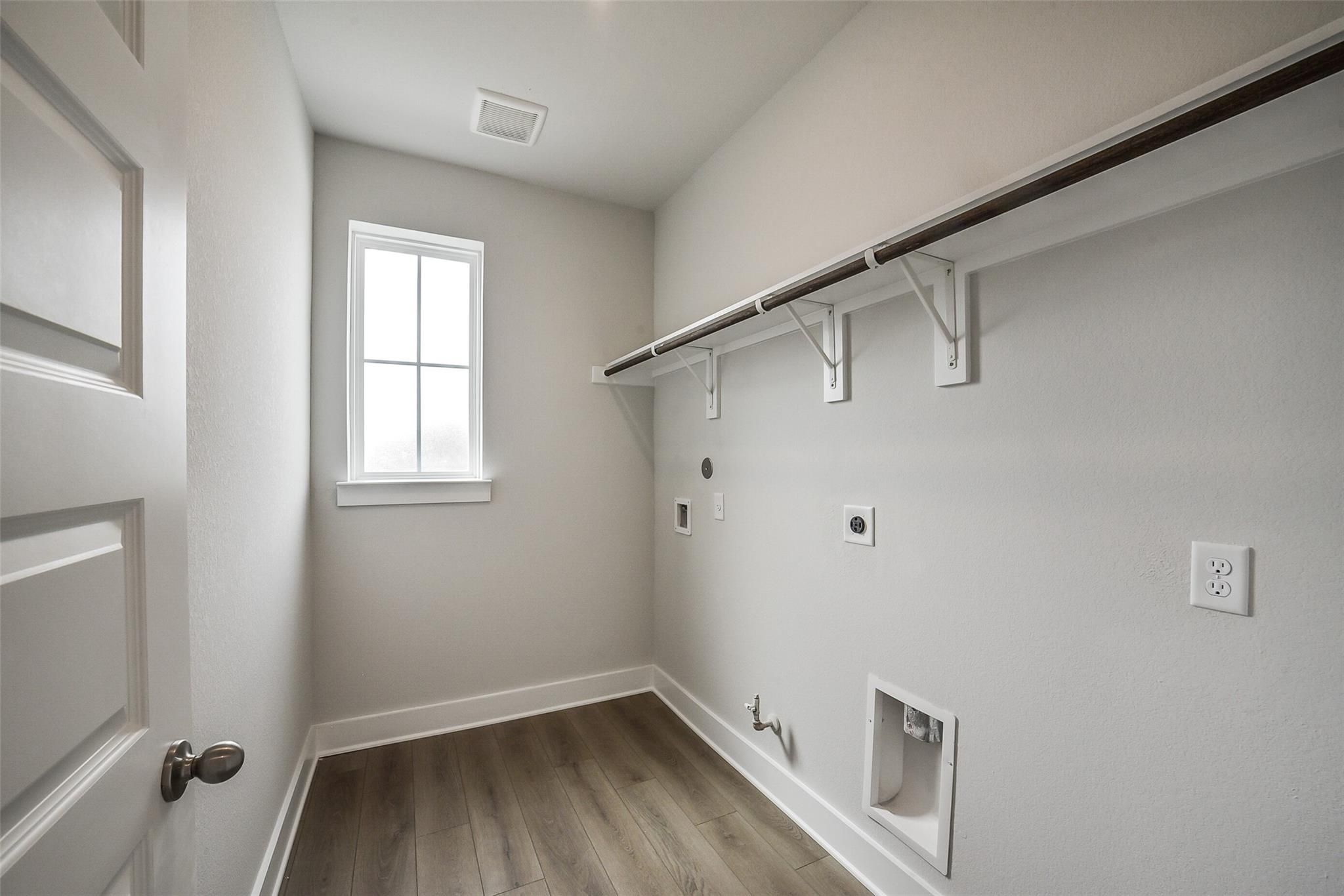 Spacious laundry room with built-in shelves, window, and utility hookups in Davidson Homes The Philip B, Rosharon, Texas
