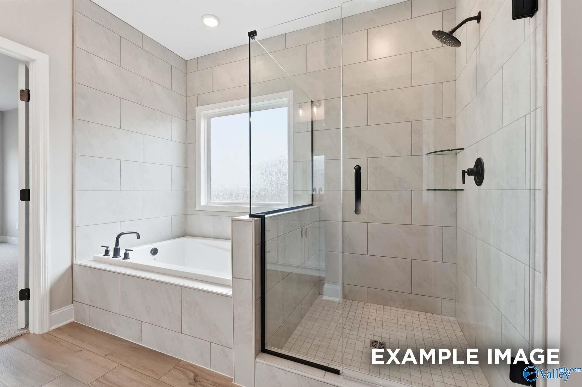 Soaking tub and glass-enclosed tile walk-in shower in master bath of Davidson Homes Rockford C, Athens, Alabama
