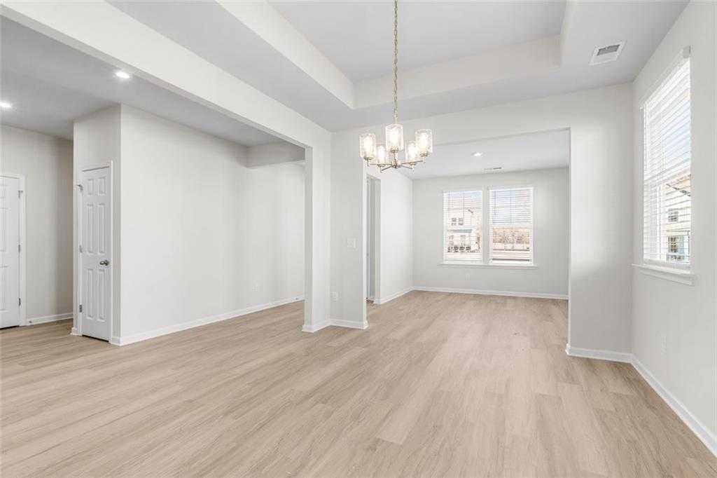 Bright open-concept living space with hardwood floors, chandelier, and arched entry in Davidson Homes The Glenwood C, Hoschton, GA