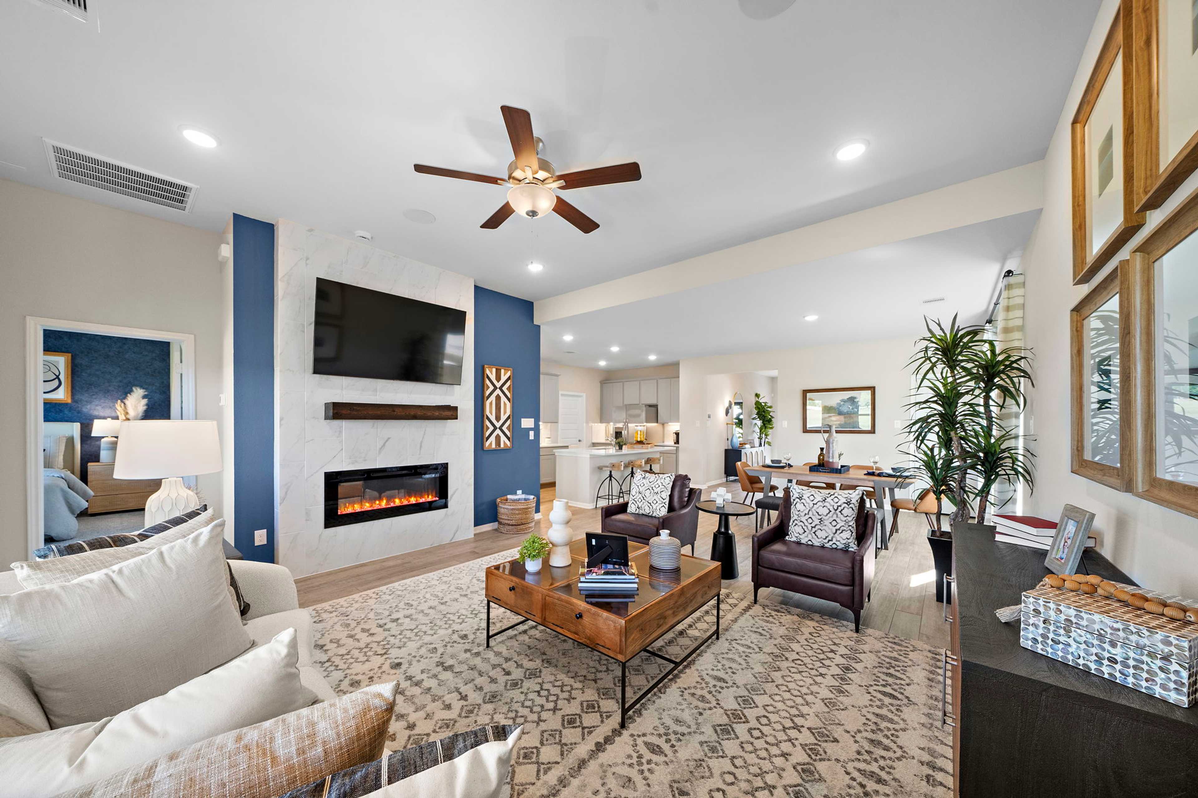 Open-concept living room in Emberly Beasley Texas by Davidson Homes with gas fireplace blue accent wall and modern seating
