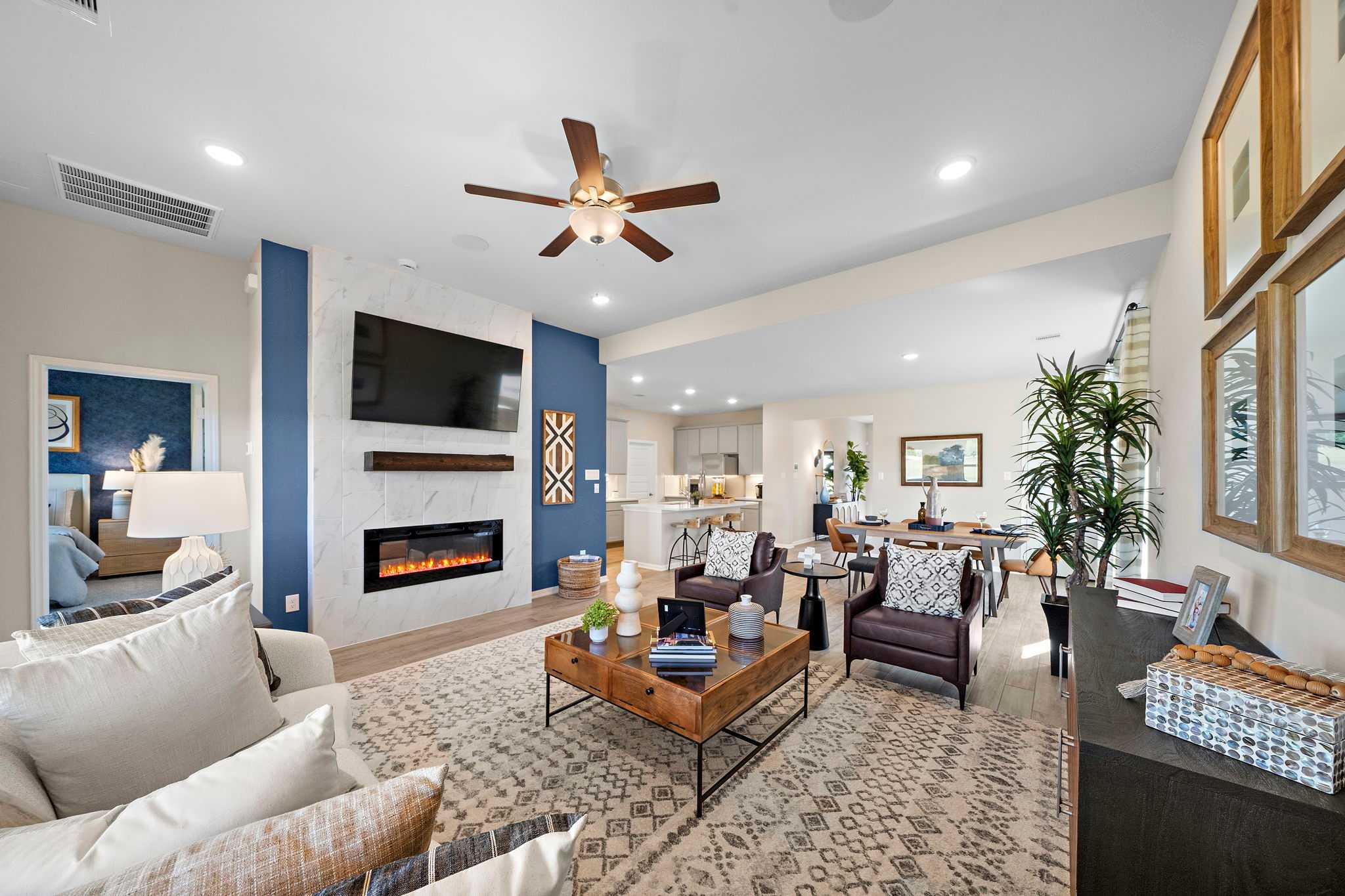 Open-concept living room in Emberly Beasley Texas by Davidson Homes with gas fireplace blue accent wall and modern seating