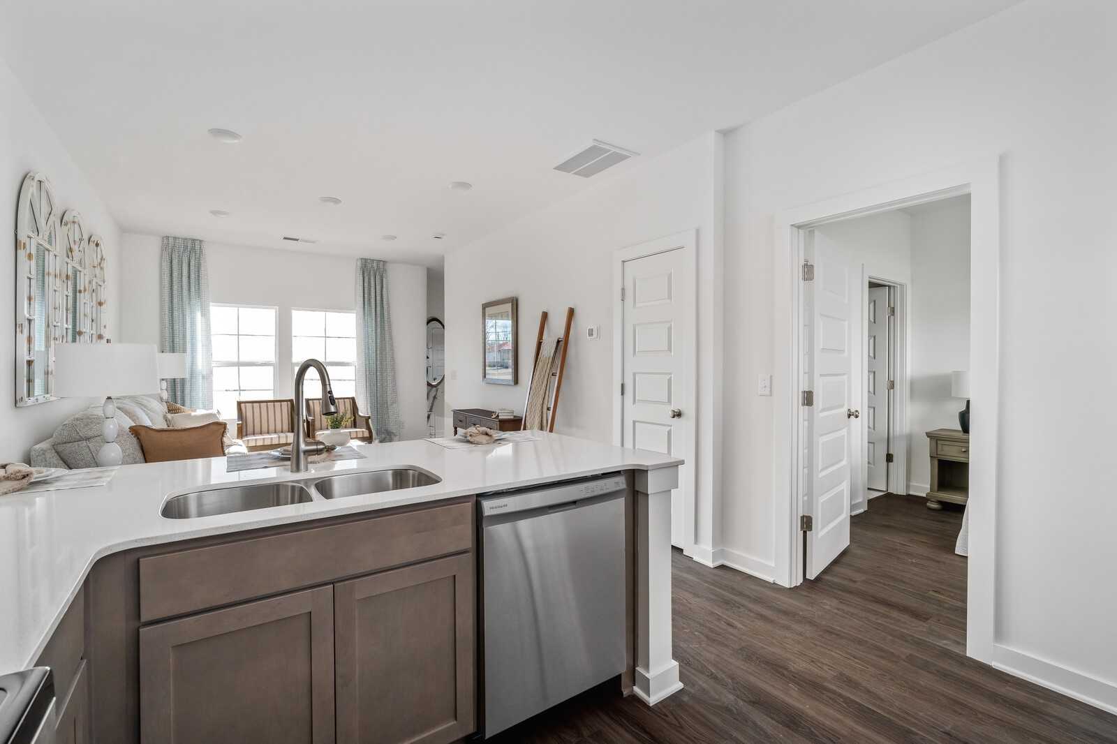 Open-concept kitchen with taupe island, double sink, stainless dishwasher in Davidson Homes The Cumberland A, Gallatin TN