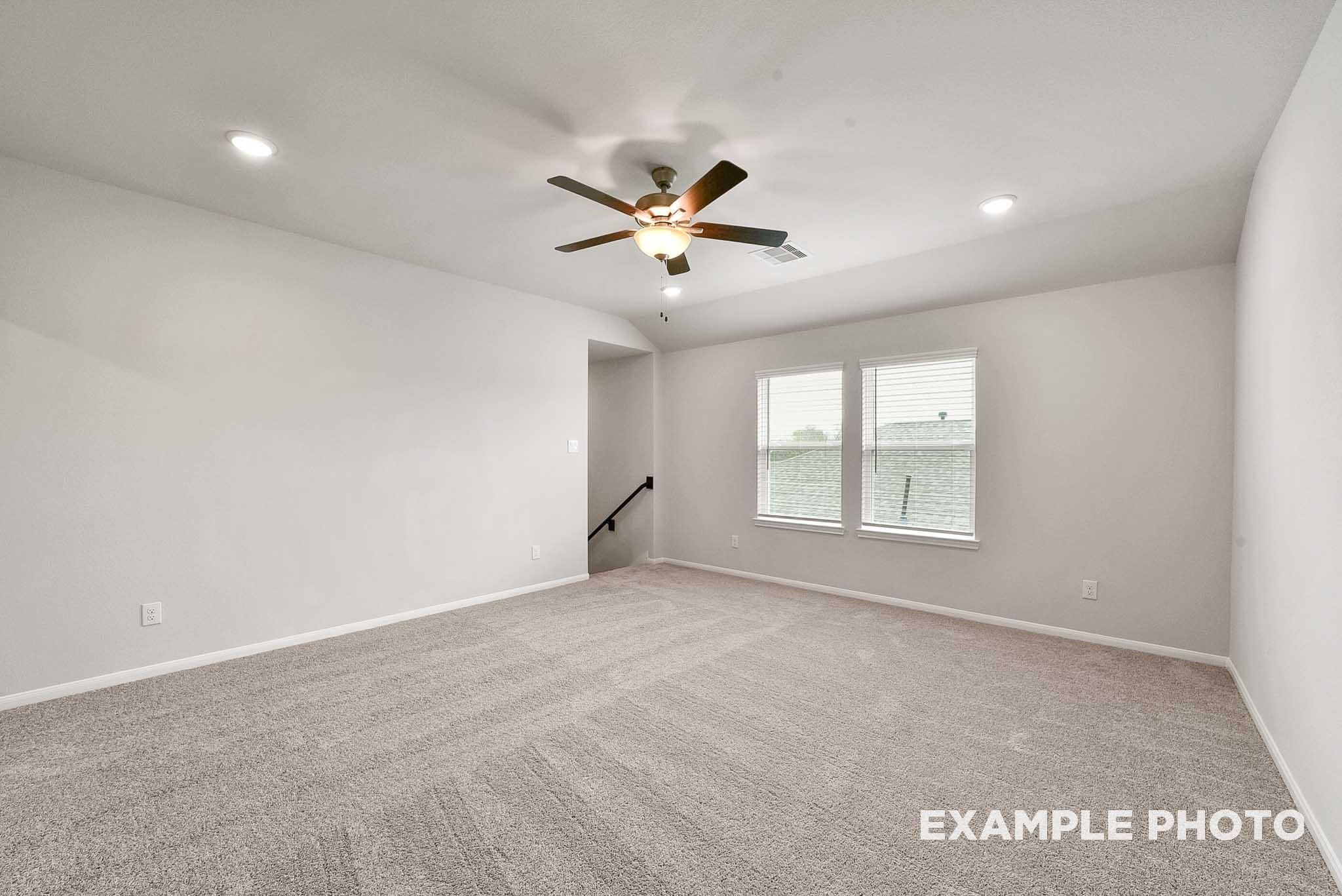 Spacious upstairs bedroom with ceiling fan, large windows, beige carpet in Davidson Homes Tierra B, Beasley, Texas