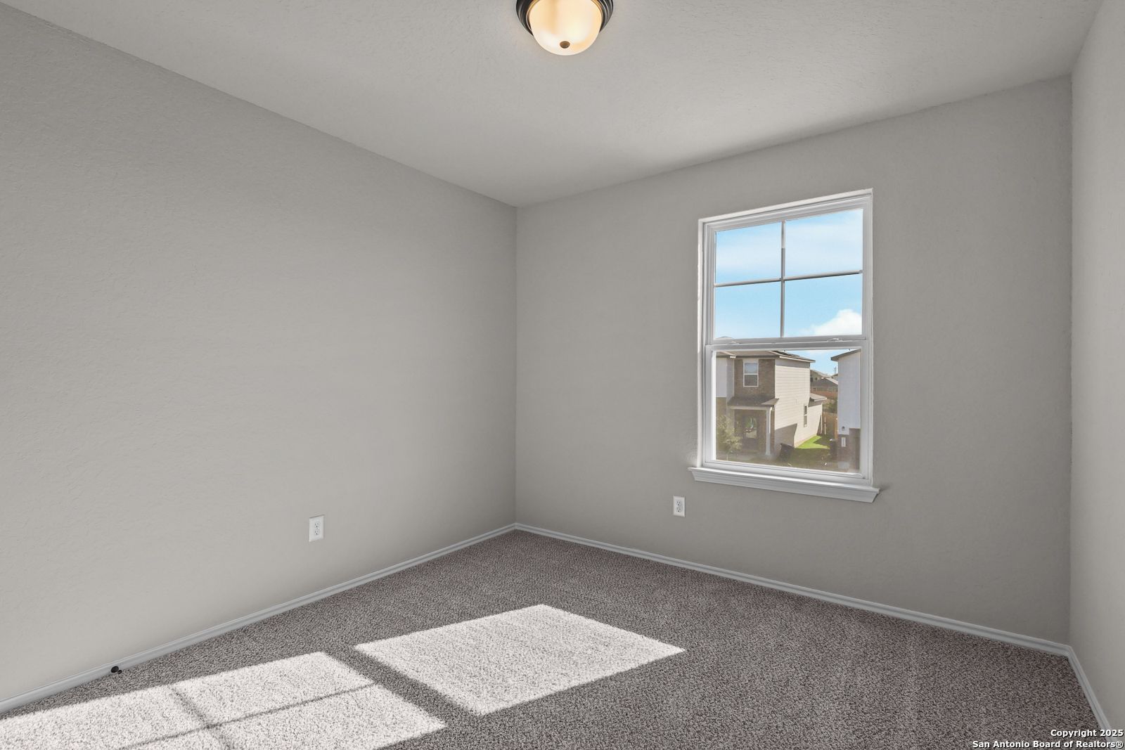 Bright empty bedroom with gray walls, beige carpet, and sunlit window in Davidson Homes The Brazos C, San Antonio