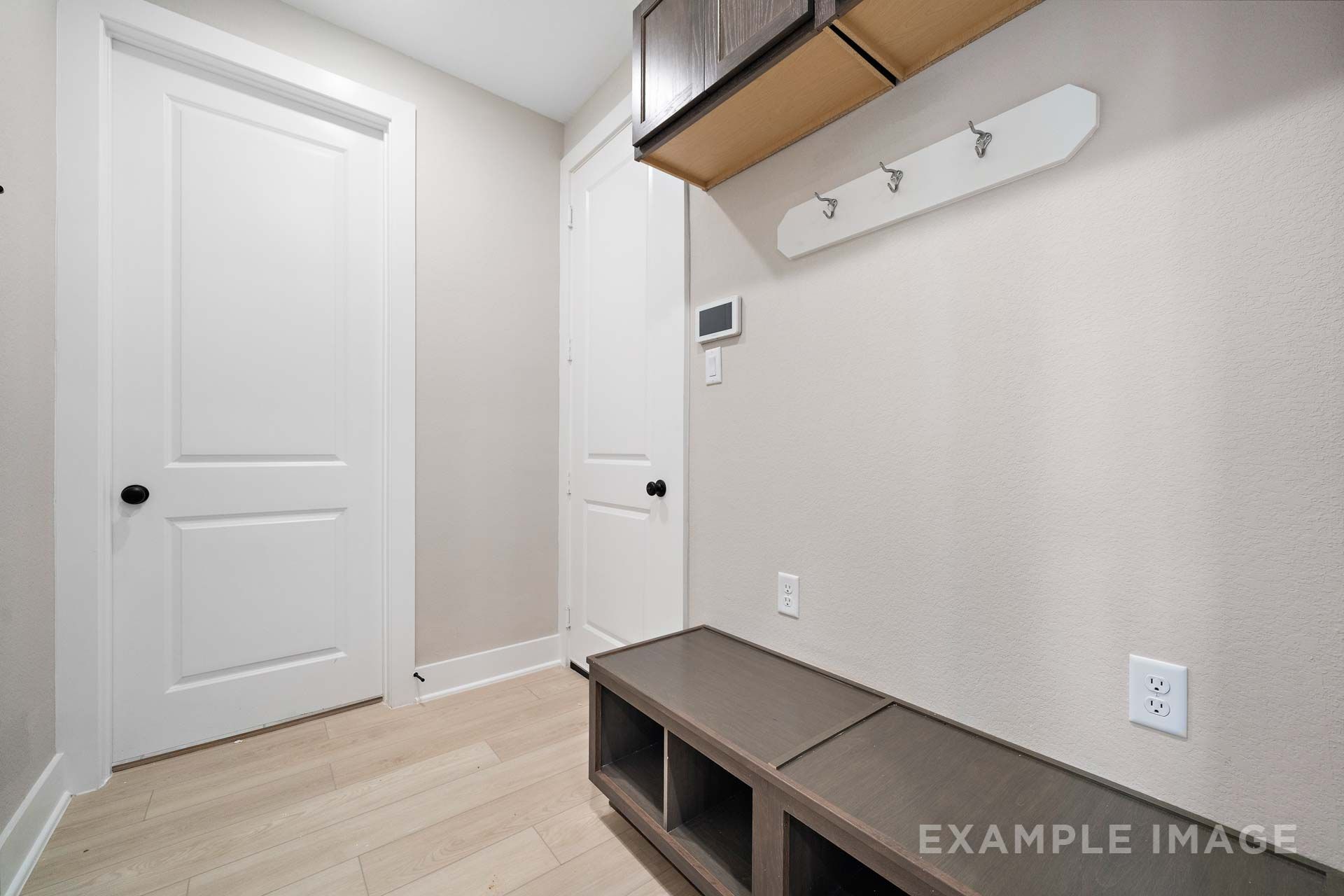 Mudroom with wooden storage bench, coat hooks, and upper cabinets in The Elizabeth by Davidson Homes, Texas City