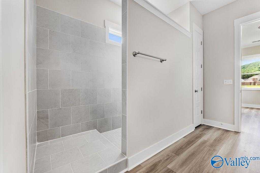 Modern walk-in shower with gray subway tiles, frosted window, and grab bar in master bath of Evermore Homes The Oxford, Owens Cross Roads
