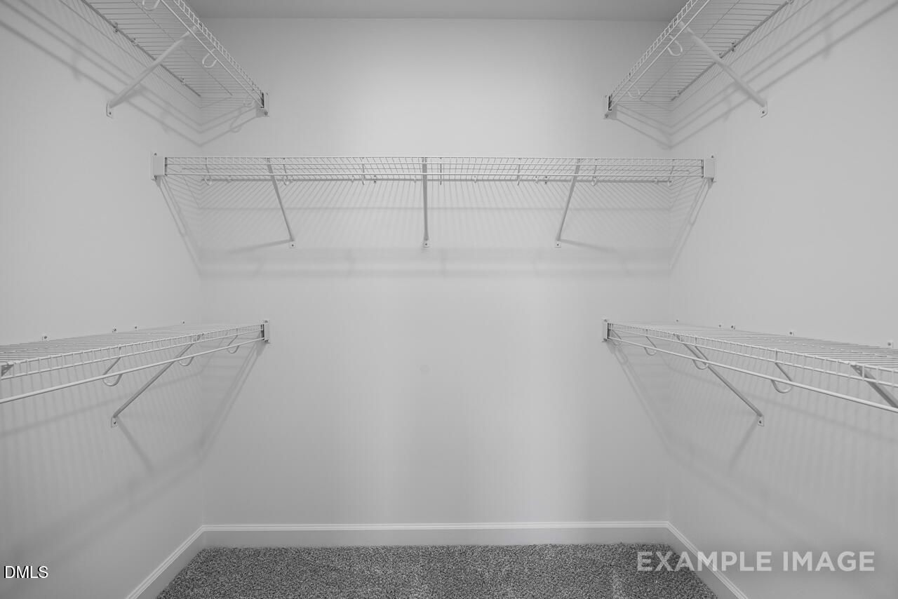 Spacious walk-in closet with wire shelving and gray carpet in master suite of The Magnolia B, Davidson Homes, Angier, NC