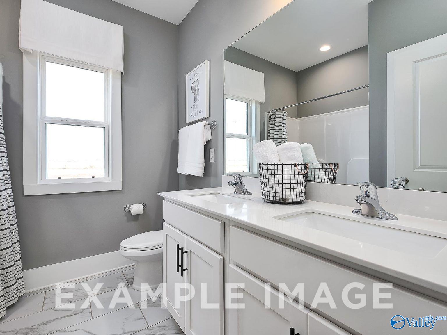 Modern master bathroom with double vanity, glass shower, and gray walls in Davidson Homes The Everett B, Toney, Alabama