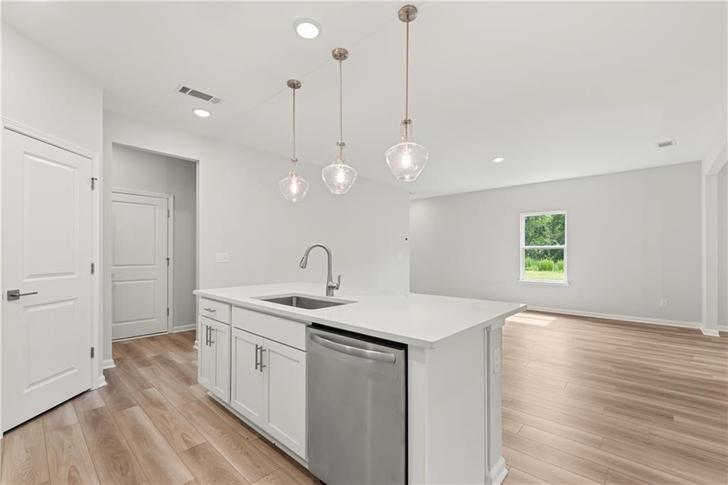 Modern kitchen island with pendant lighting and stainless steel appliances in The Russell A plan at Cedar Farms, Winder.