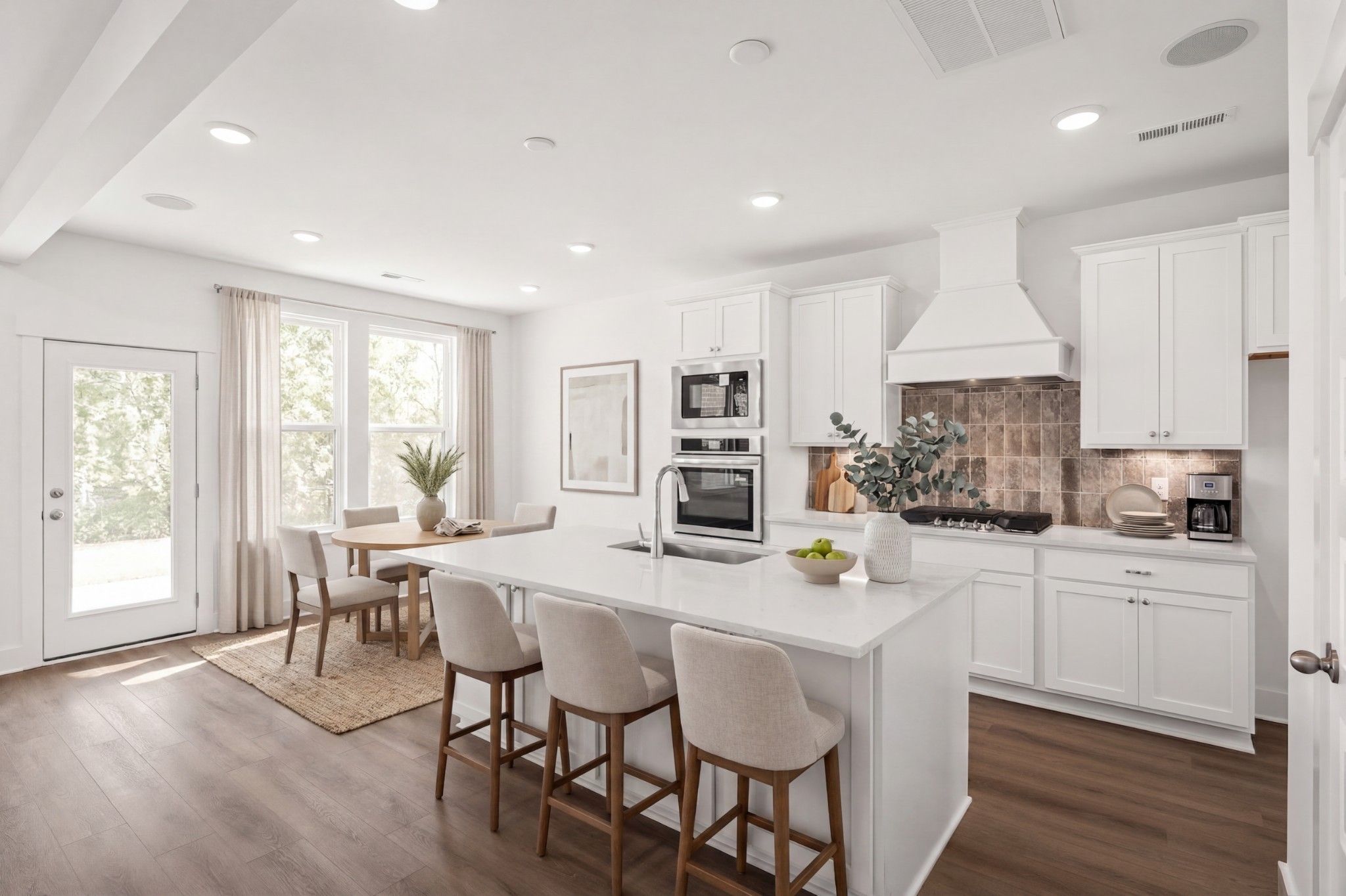 Modern kitchen with white island, stainless appliances, and dining area in The Willow D floor plan, Benders Cove, Mt. Juliet.