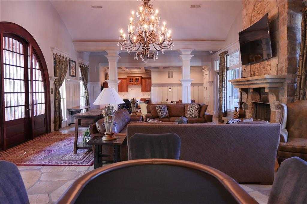 Grand living room with stone fireplace, crystal chandelier, leather sofas in Davidson Homes The Seaside B, Woodstock, GA