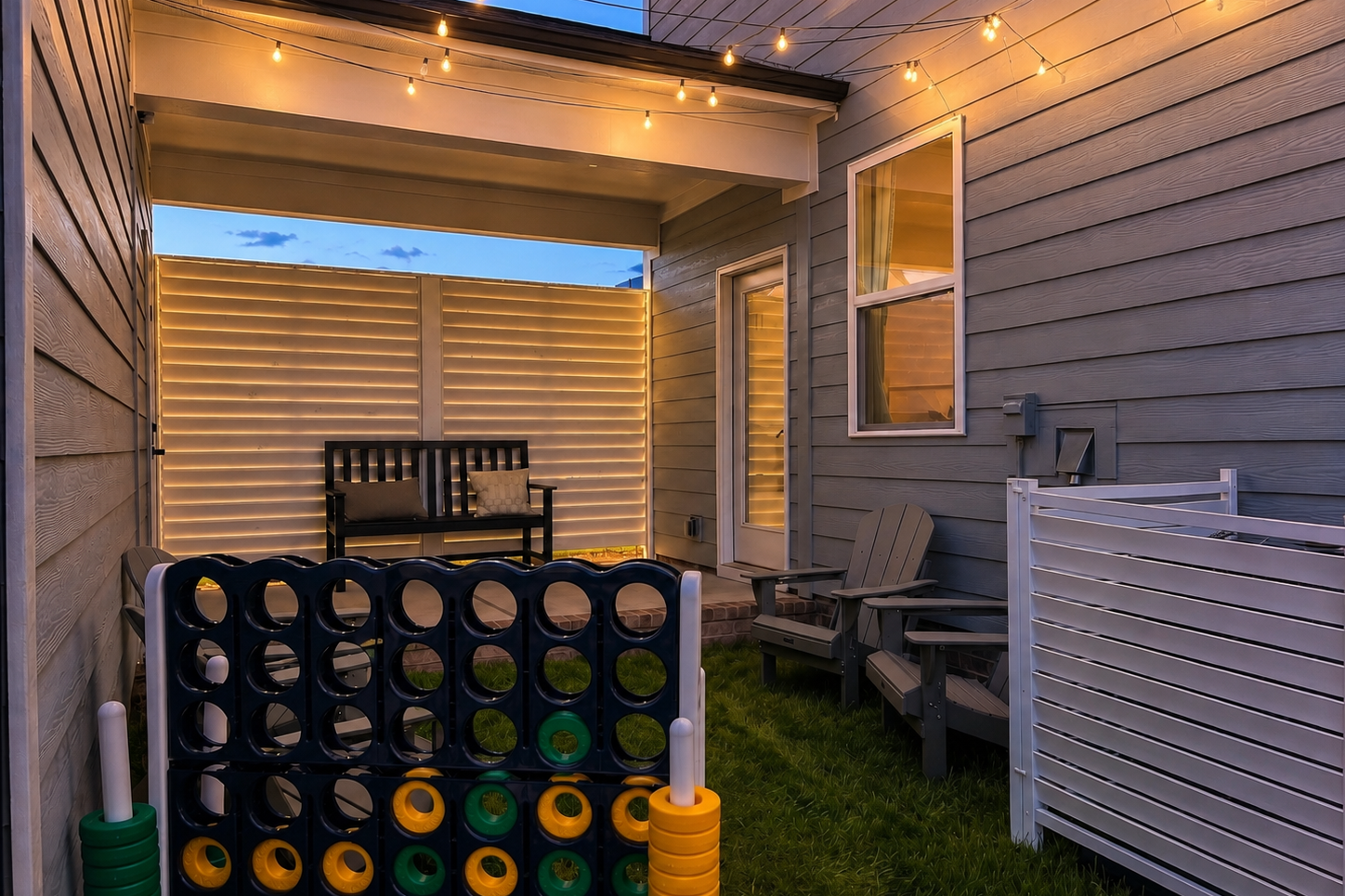 Cozy backyard patio at Forestville Yard in Knightdale, NC by Davidson Homes with string lights and lawn games.
