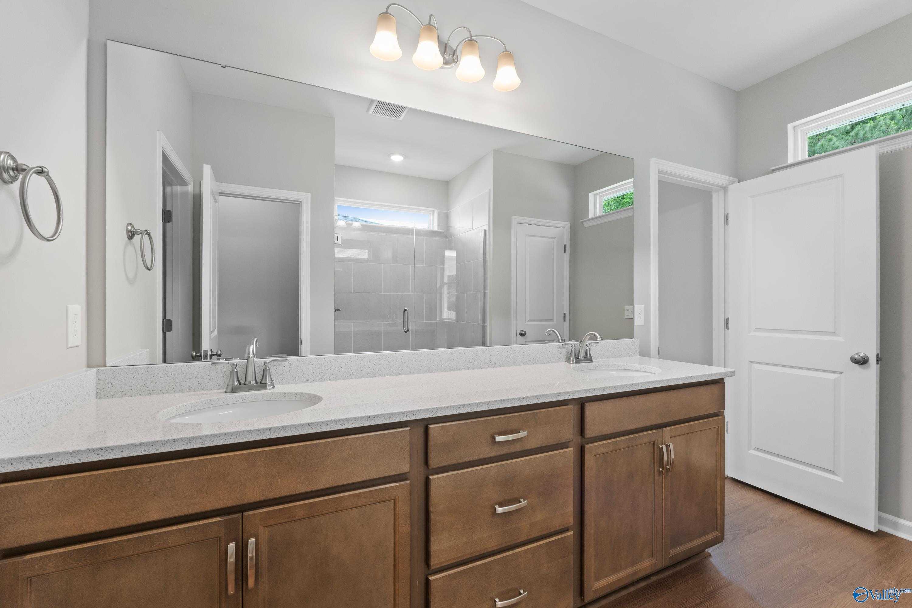 Elegant master bathroom featuring double vanity with quartz countertop and large mirror in Davidson Homes The Stella, Hazel Green, Alabama
