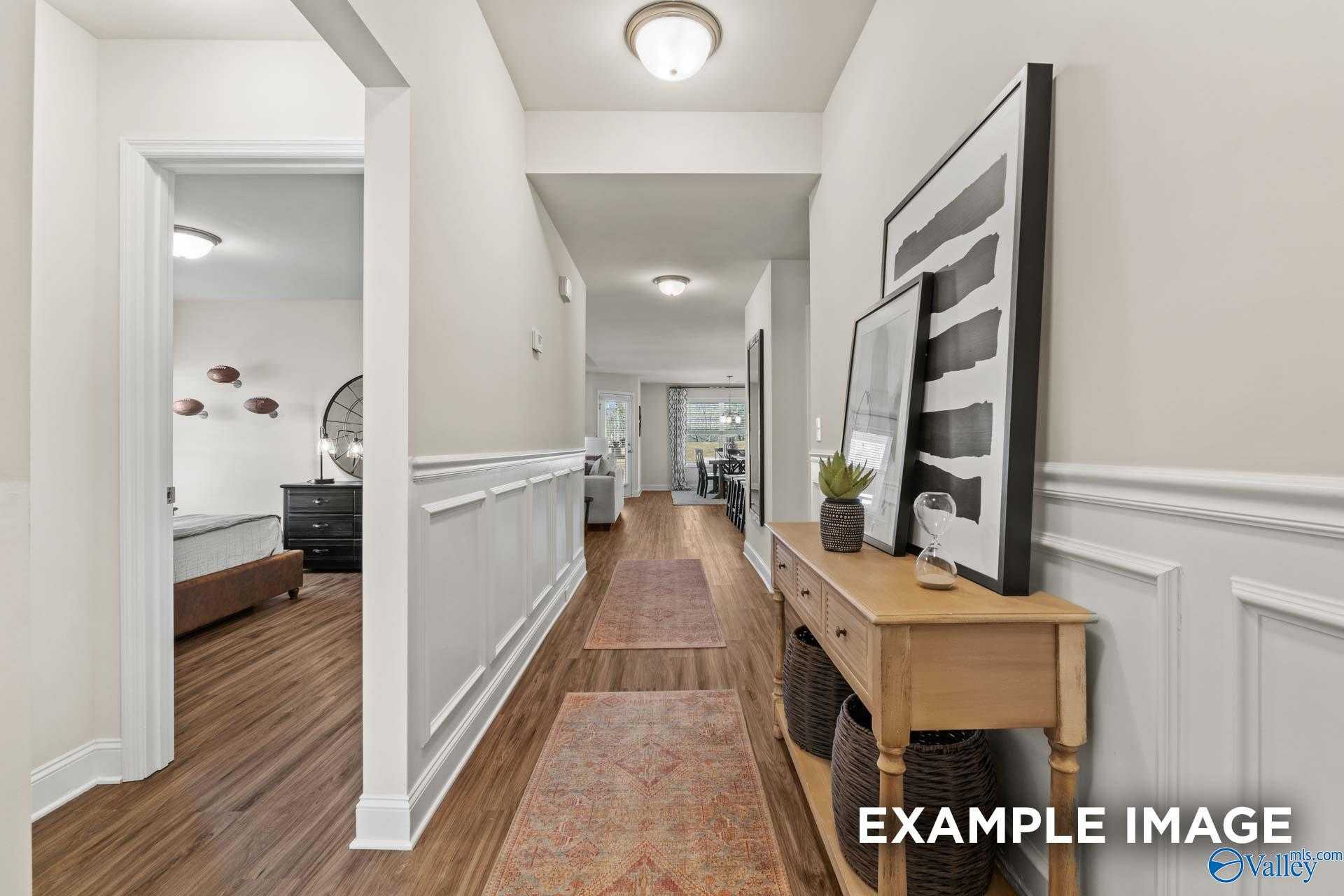Elegant hallway with wainscoting, hardwood floors, runner rug, and console table in Davidson Homes The Franklin C, New Market, Alabama