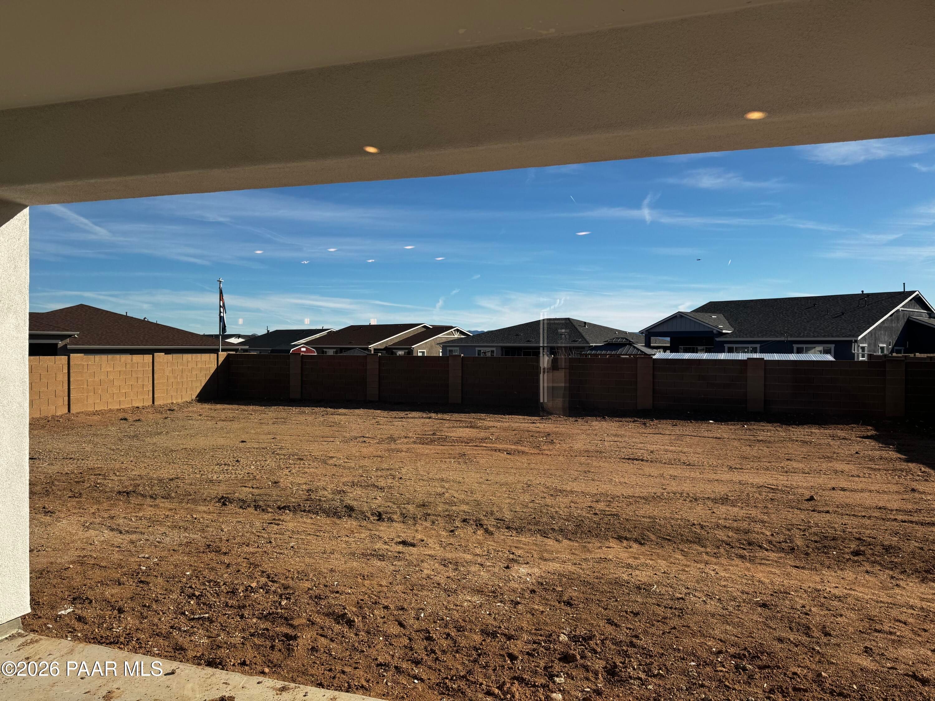 Expansive empty backyard with tan block fence, covered patio, and neighboring homes in Davidson Homes The Daybreak B, Westwood, Prescott, Arizona