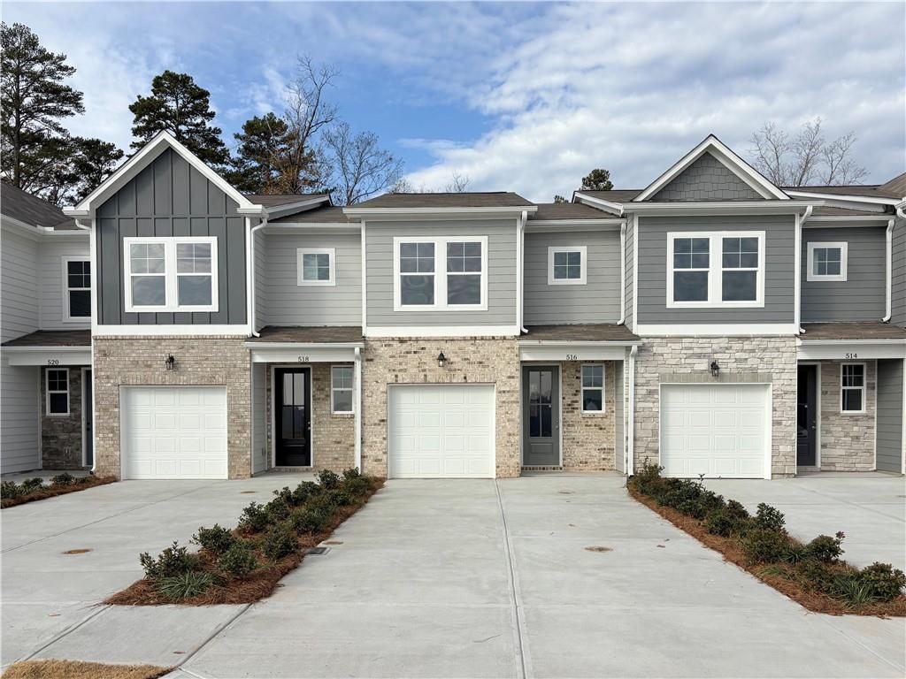 Three modern 2-story gray townhomes with 1-car garages, brick accents, and driveways in Stegall Village, Emerson, Georgia