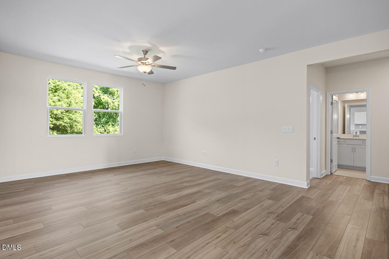 Spacious owner's suite with wood-look flooring, ceiling fan, and private bath in Davidson Homes Willow C, Zebulon NC