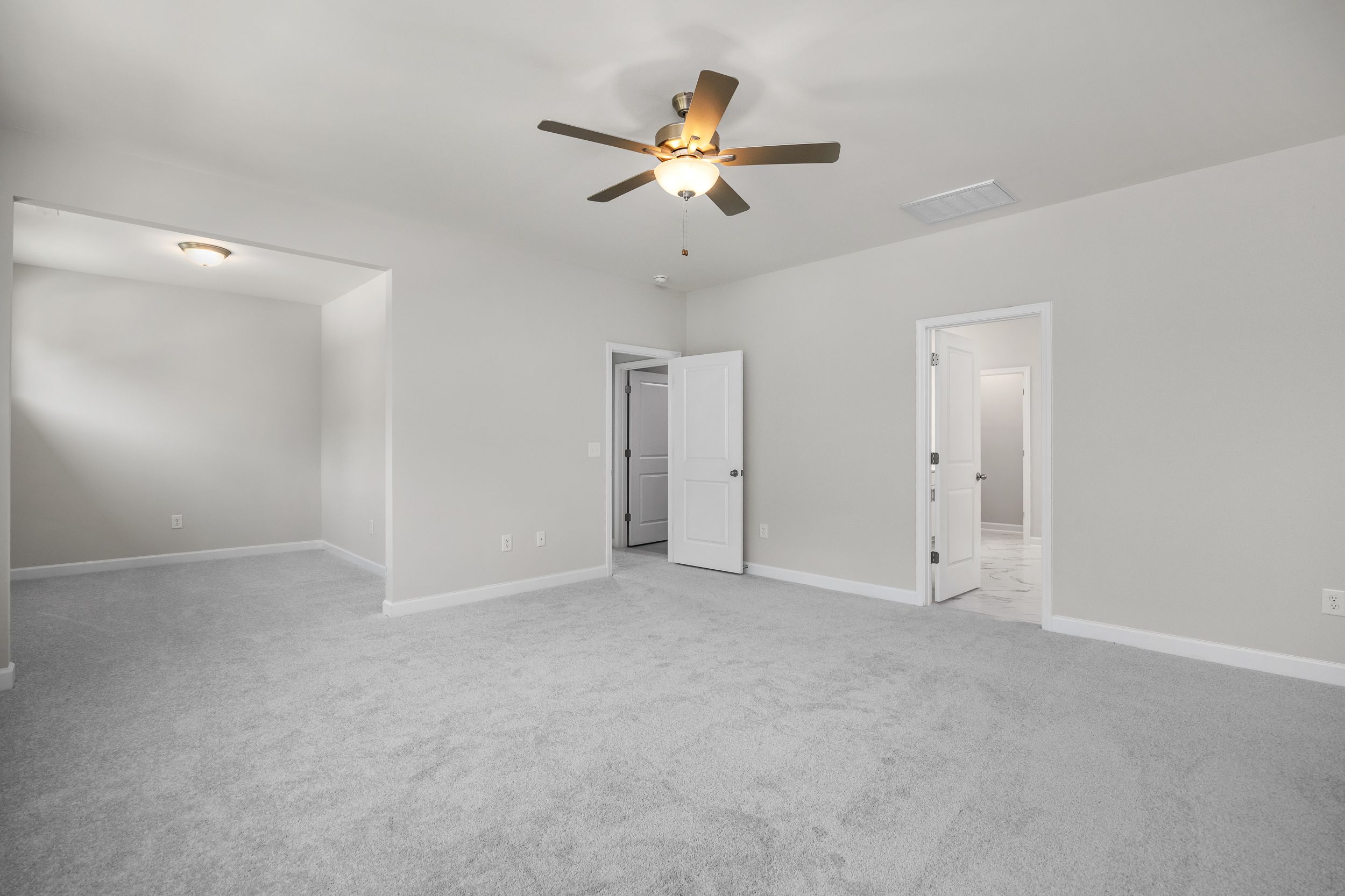 Spacious upper-floor master suite in The Aspen C with neutral gray walls, beige carpet, ceiling fan, and double doorways