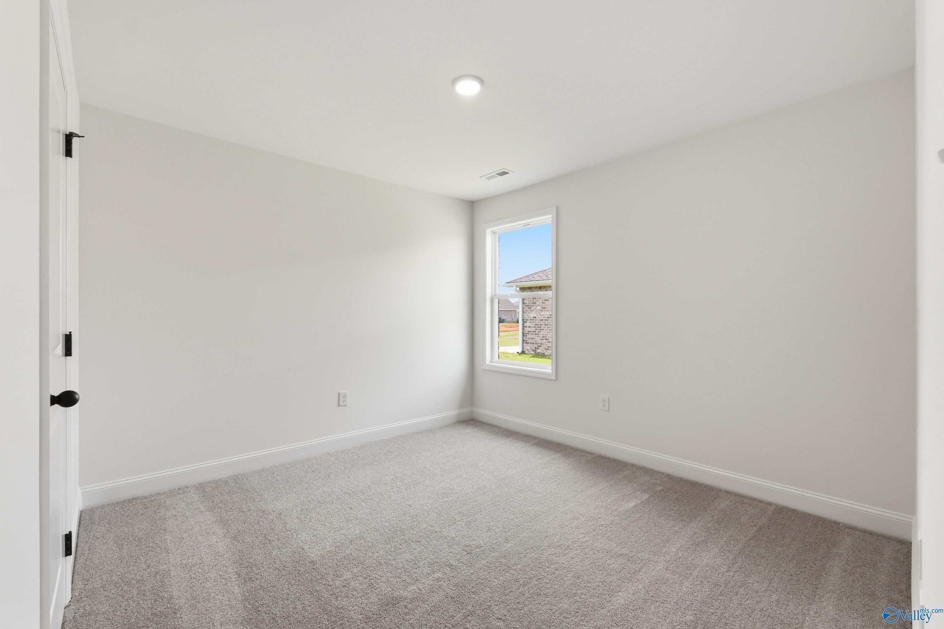 Bright, carpeted bedroom with neutral walls in The Franklin floor plan at Heritage Lakes, New Market, Alabama.