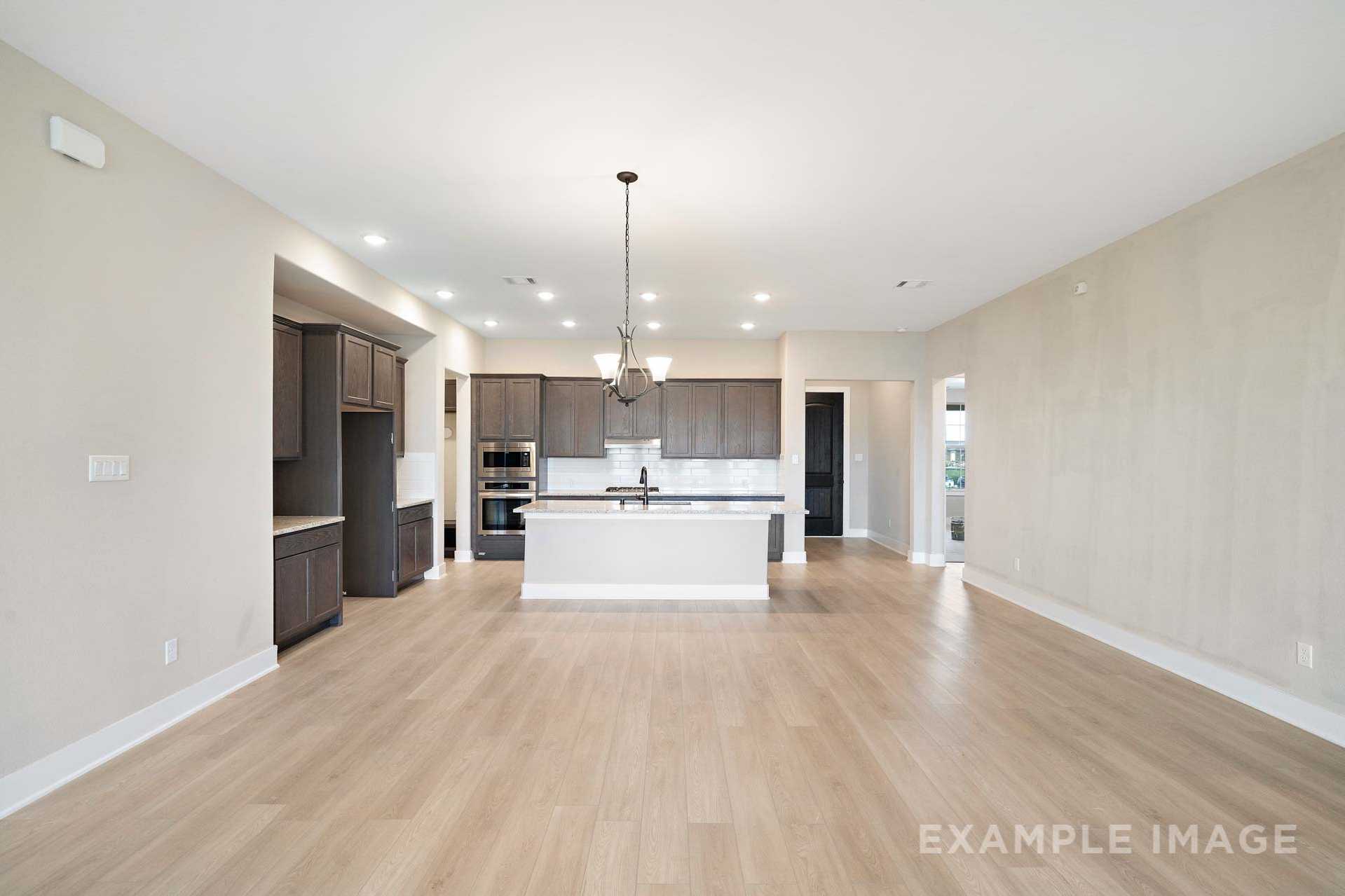 Open-concept kitchen in The Elizabeth A Davidson Homes design featuring white island, dark cabinets, hardwood floors