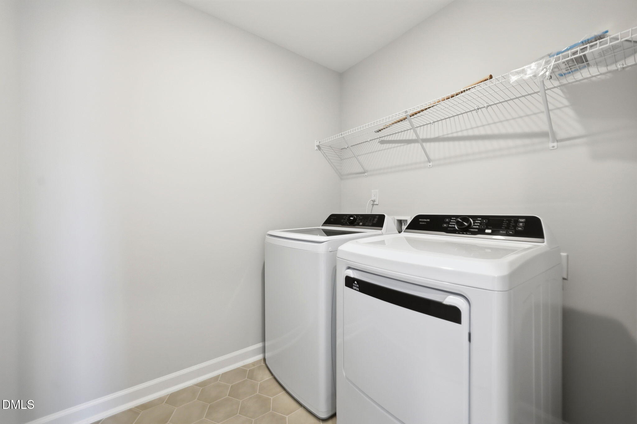 Laundry room with white washer and dryer, tile flooring, and wire shelving in Davidson Homes Avery floor plan, Knightdale.