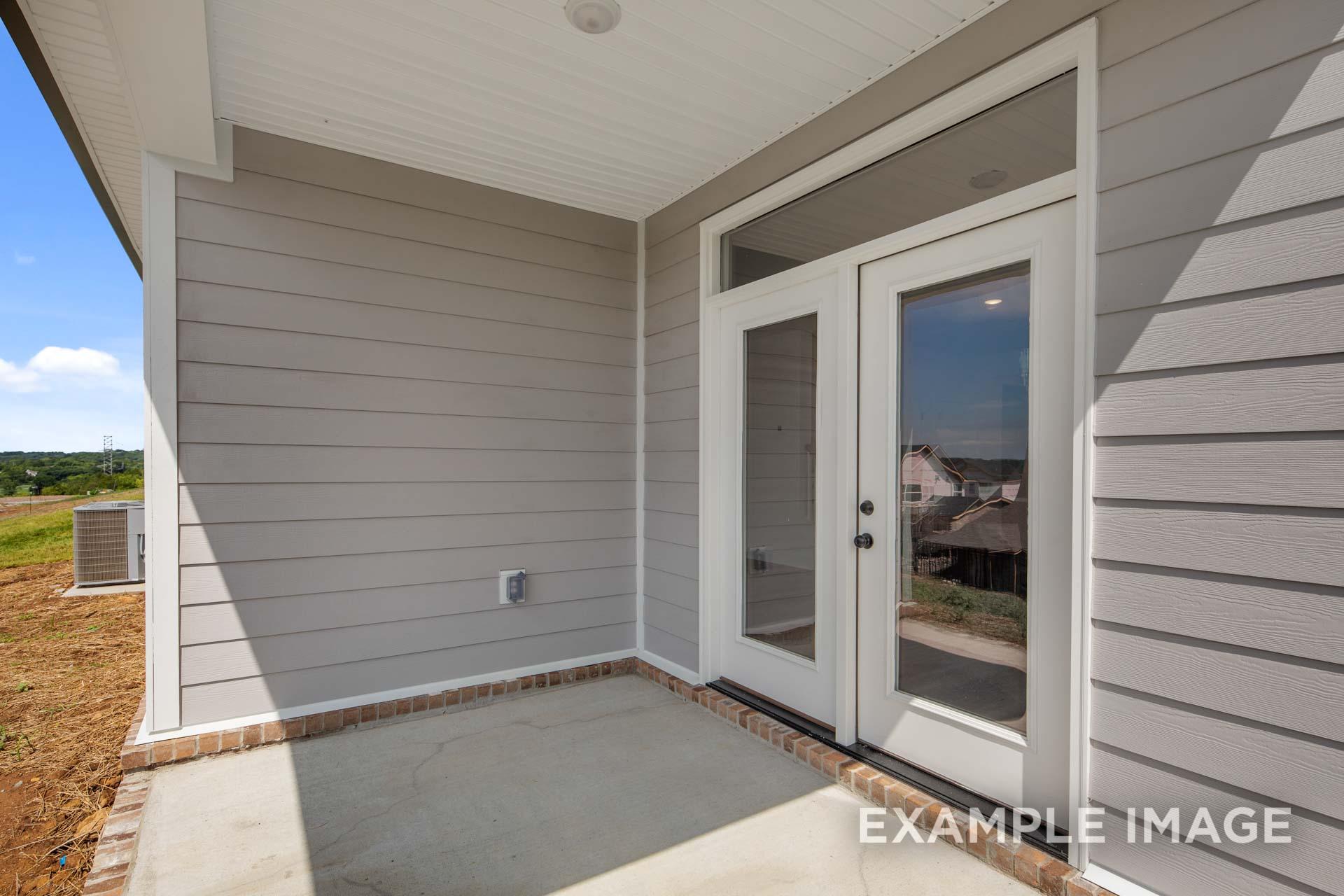 Front entrance of The Ash C home with covered porch, double glass doors, and beige siding exterior in Mt. Juliet