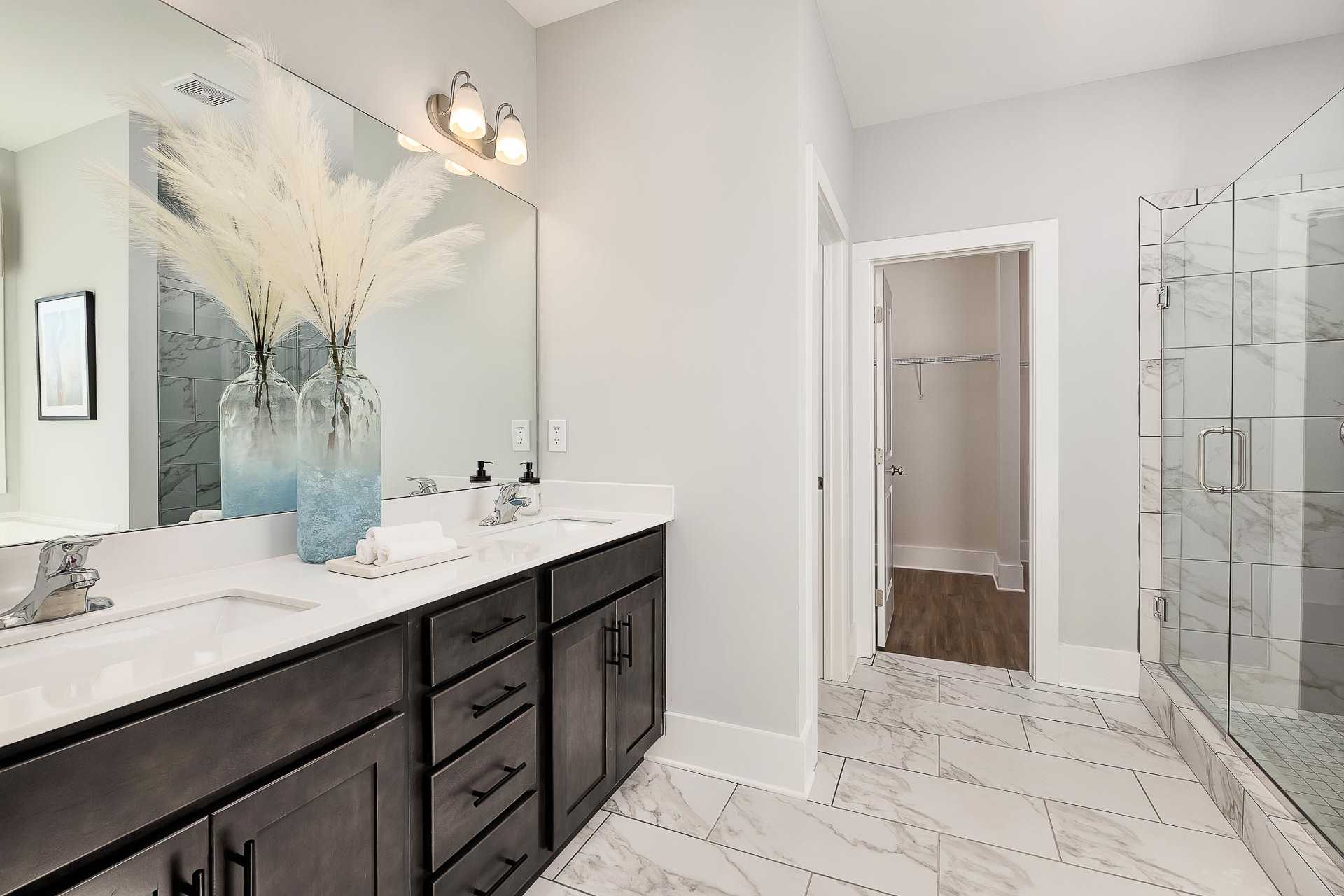 Spacious master bathroom at Newby Chapel in Athens Alabama with double dark wood vanity, glass shower, and pampas grass decor