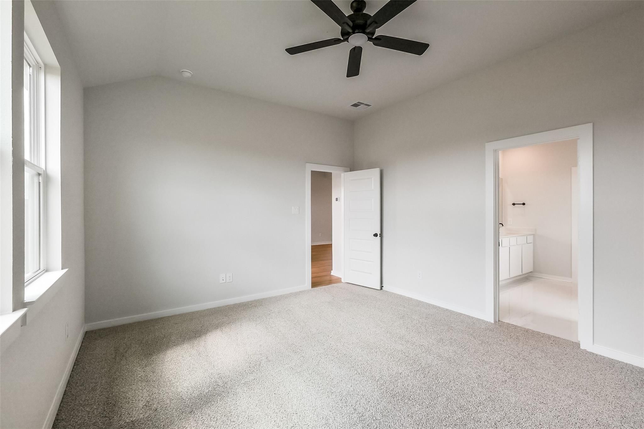 Spacious secondary bedroom with ceiling fan, carpet flooring, and en-suite bathroom in Davidson Homes The Tierra B, Beasley, Texas
