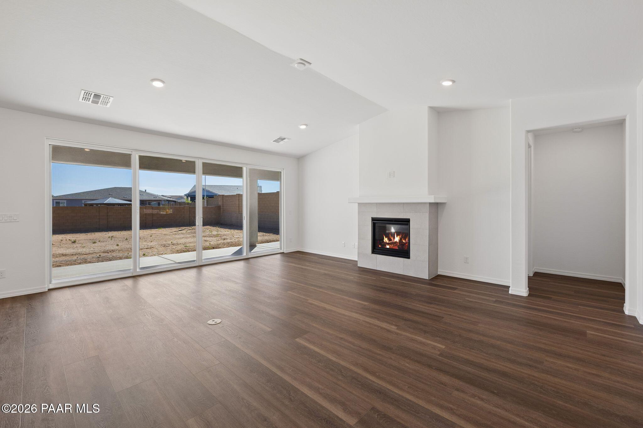 Bright living room with gas fireplace, hardwood floors, and sliding doors to desert backyard in Davidson Homes The Monarch A, Prescott AZ