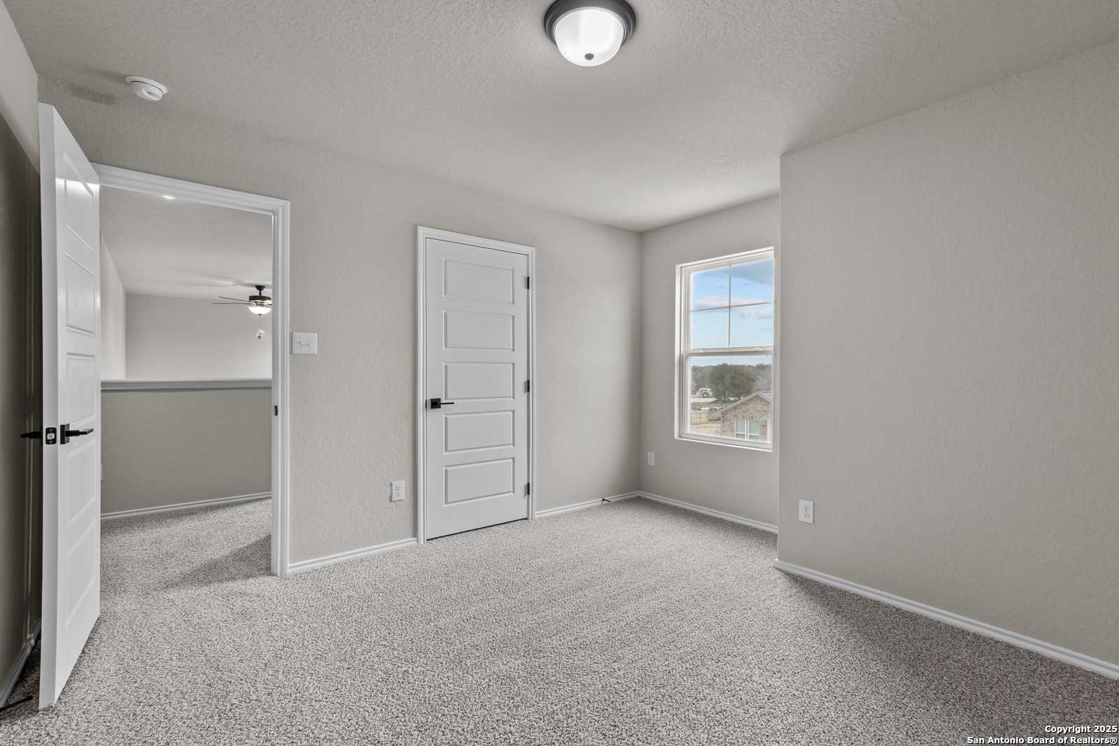 Bright secondary bedroom with neutral walls, carpet flooring, ceiling fan, and window view in Davidson Homes The Murray I, San Antonio
