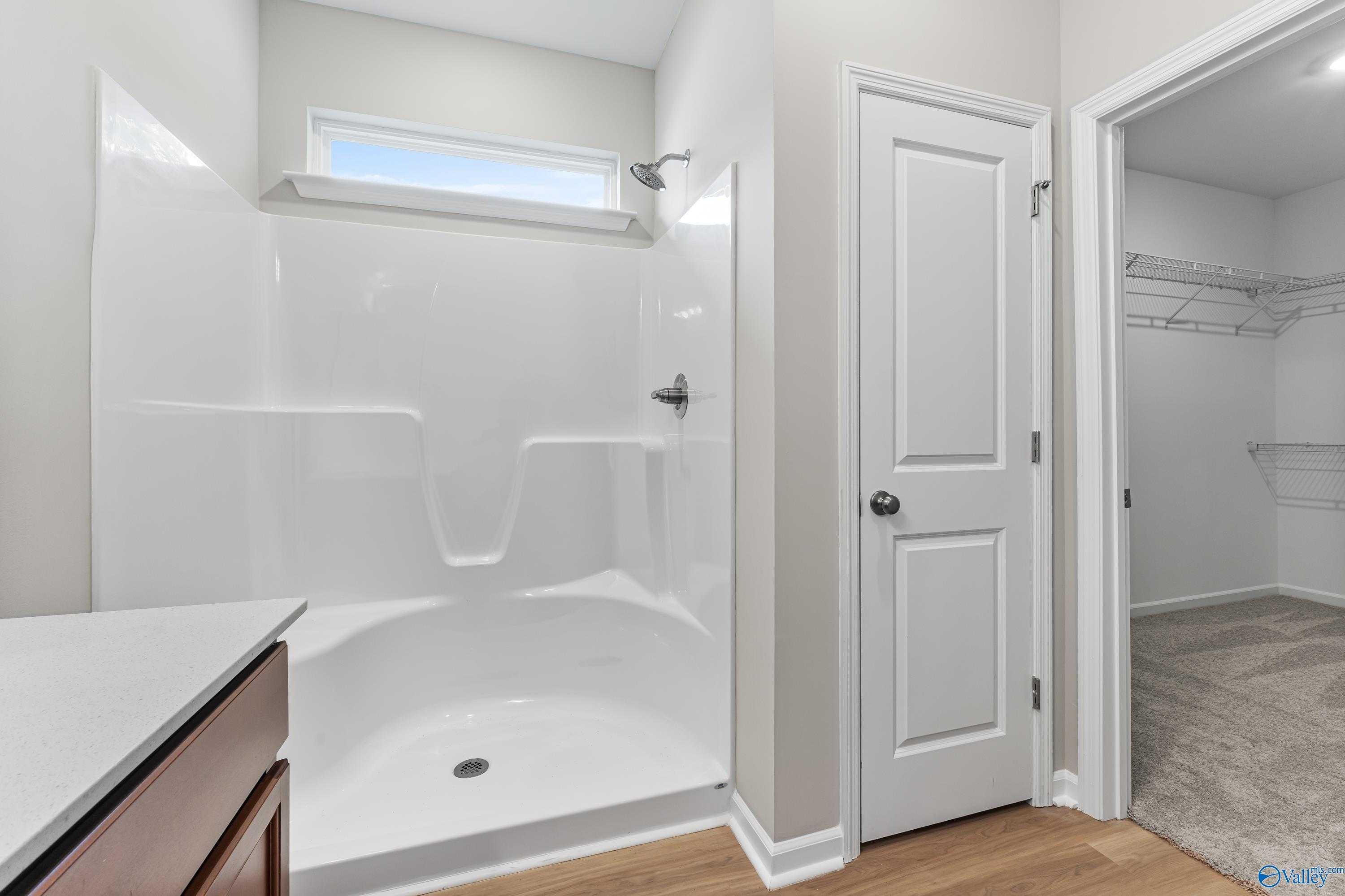 Contemporary bathroom with frameless glass shower, single vanity, and open walk-in closet in The Aurora 4-bedroom home by Davidson Homes, Fayetteville TN