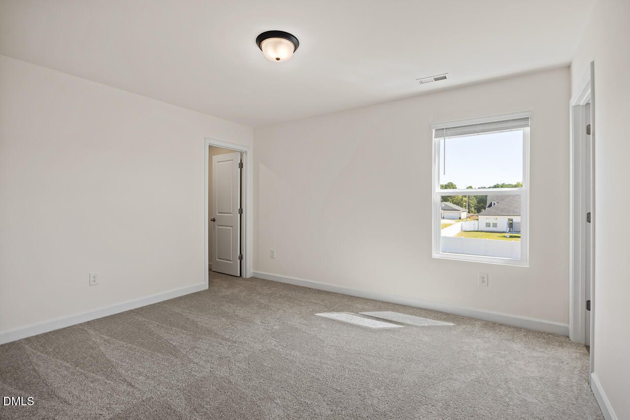Bright empty bedroom with plush gray carpet, white walls, and sunny window in Davidson Homes' Hickory II B, Lillington, NC