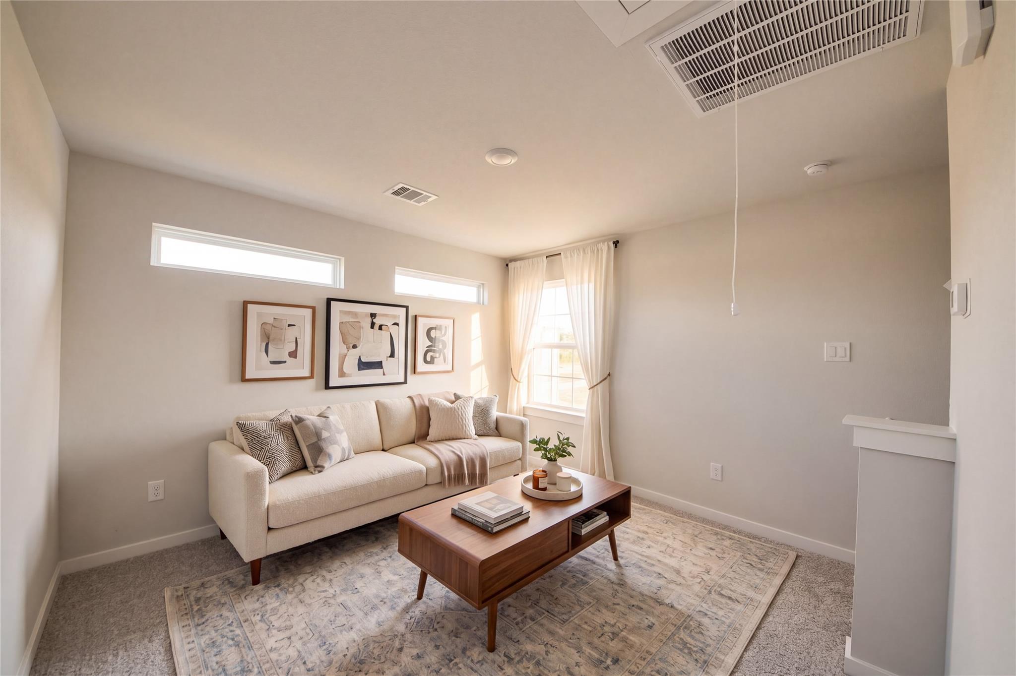 Bright living room with cream sofa, wood coffee table, and natural light in Davidson Homes The Sabine F, Cleveland, Texas